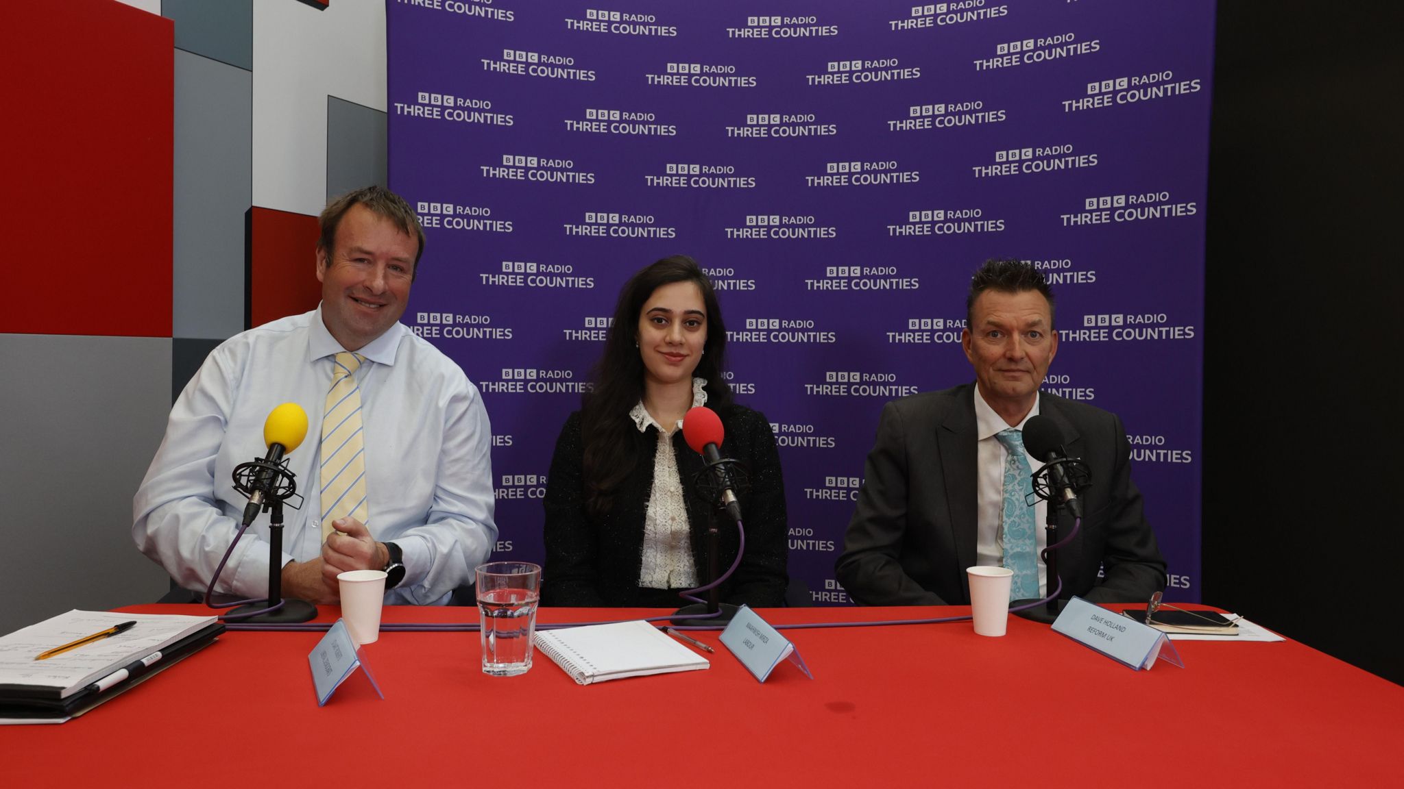 Three candidates in the Mid Bedfordshire debate smiling at the camera