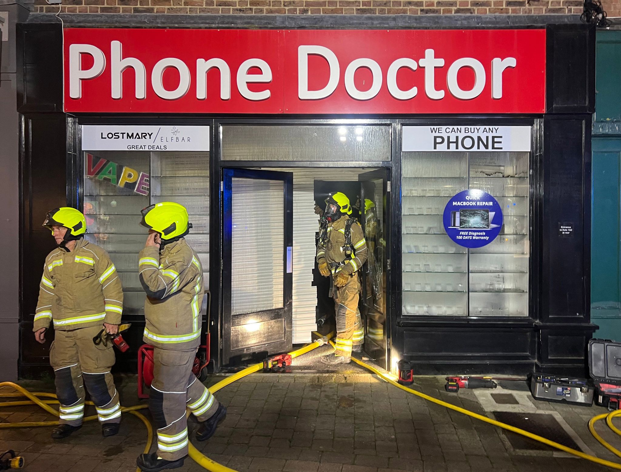 Three firefighters leaving a phone shop