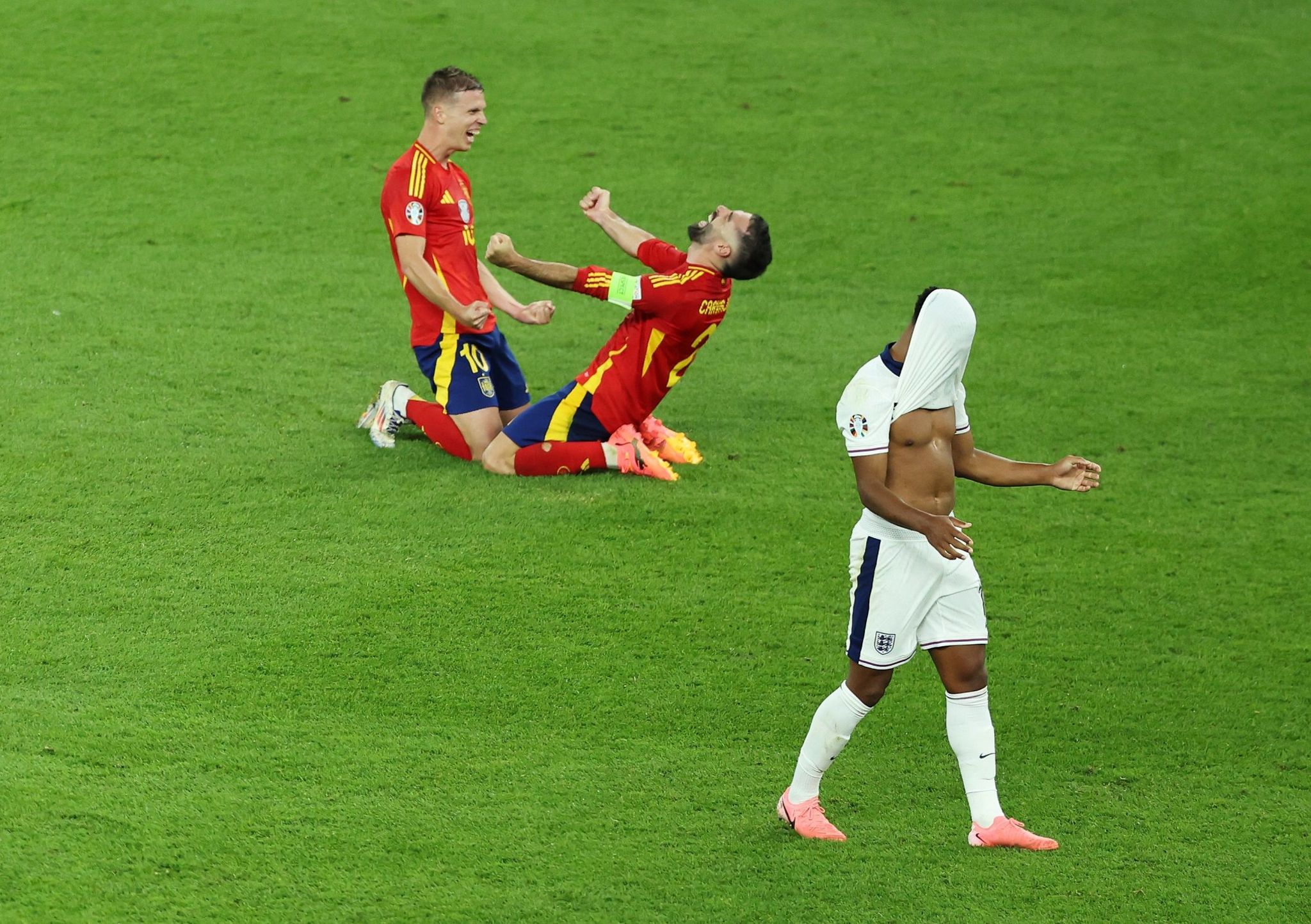 Dani Olmo and Dani Carvajal celebrate Spain's victory over England in the Euro 2024 final as Ollie Watkins covers his face with his shirt