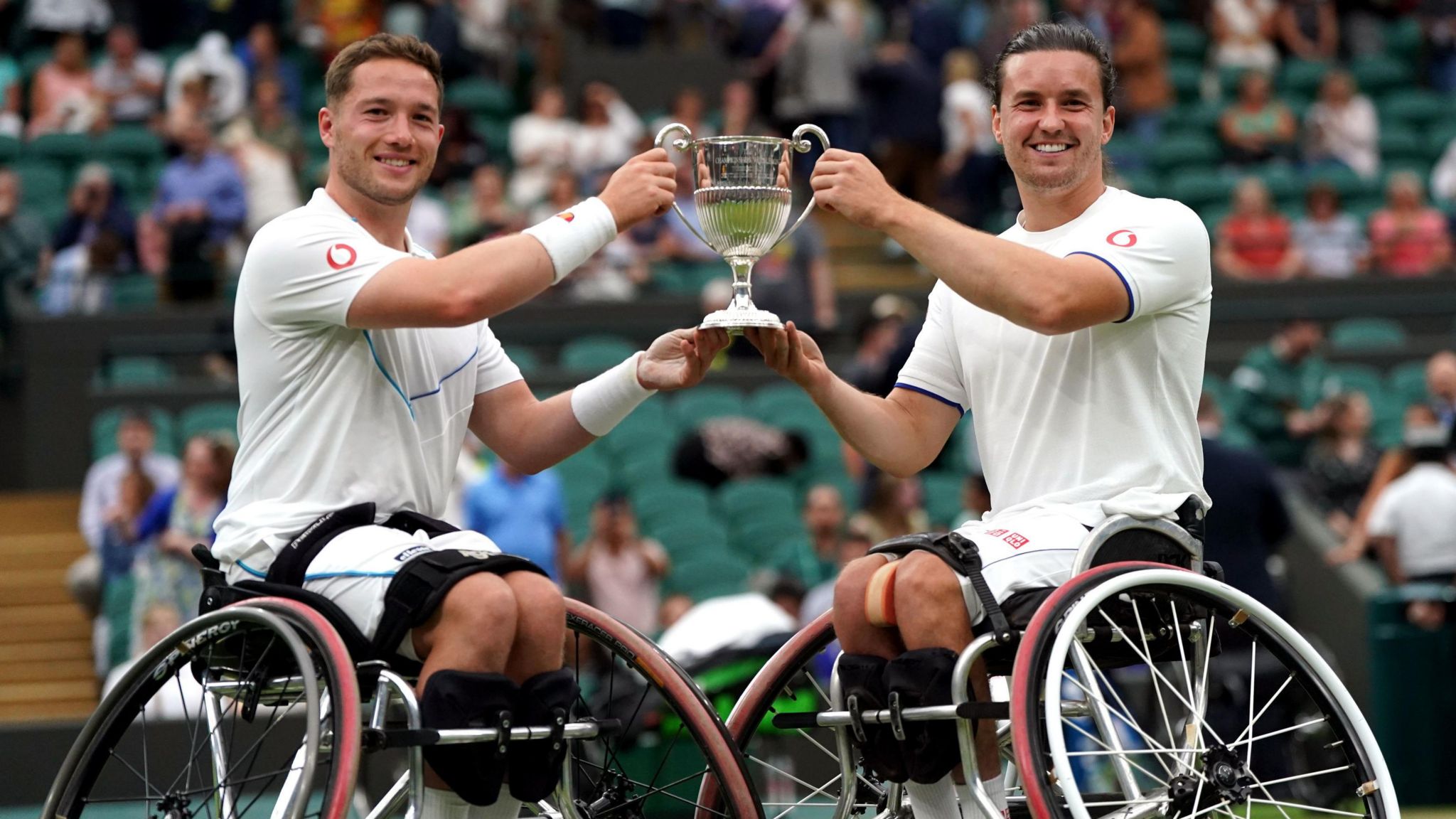 Paralympic athletes Alfie Hewett and Gordon Reid, hold tennis trophy.