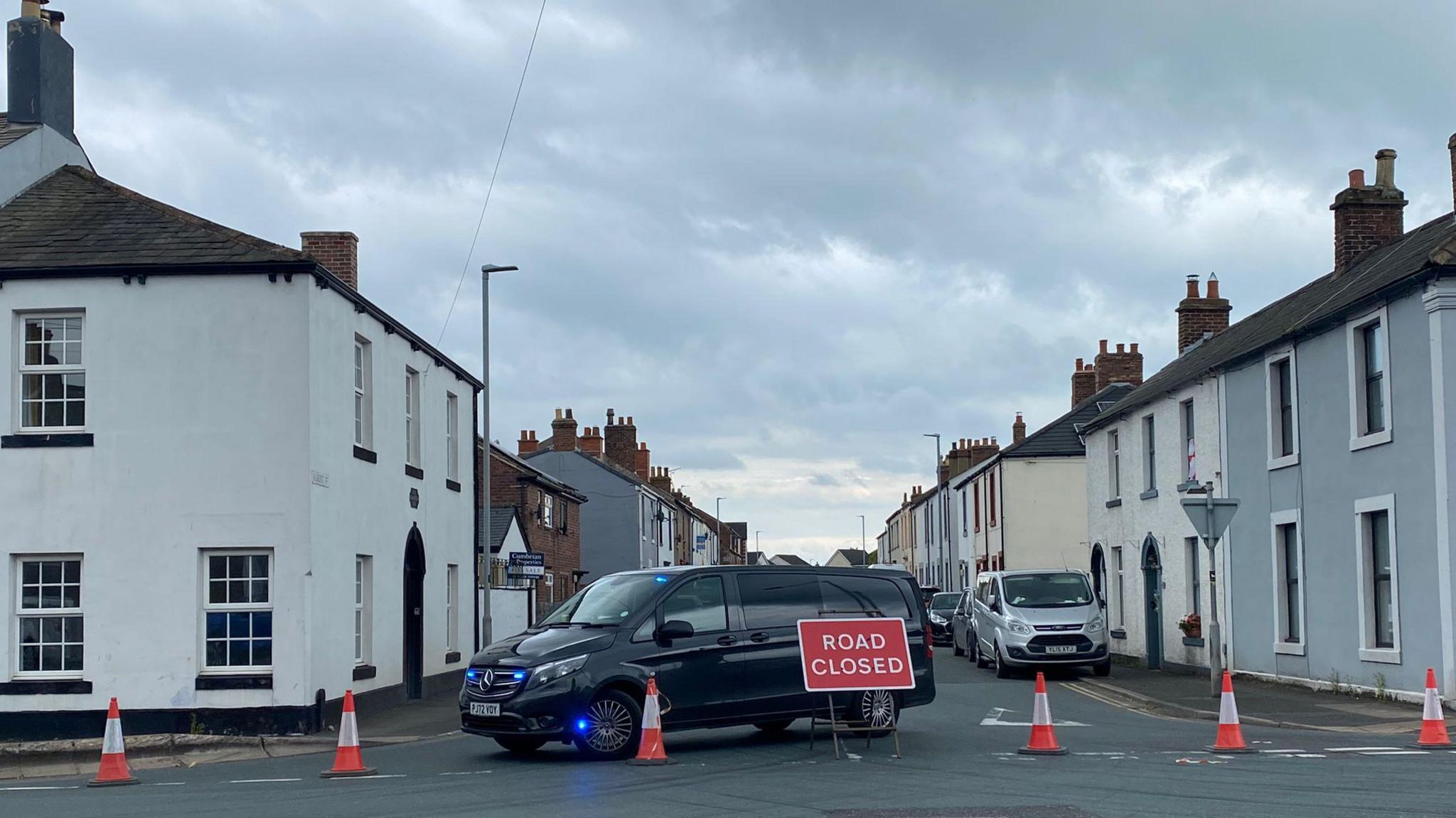 Cones and a vehicle parked across the road behind a Road Closed sign