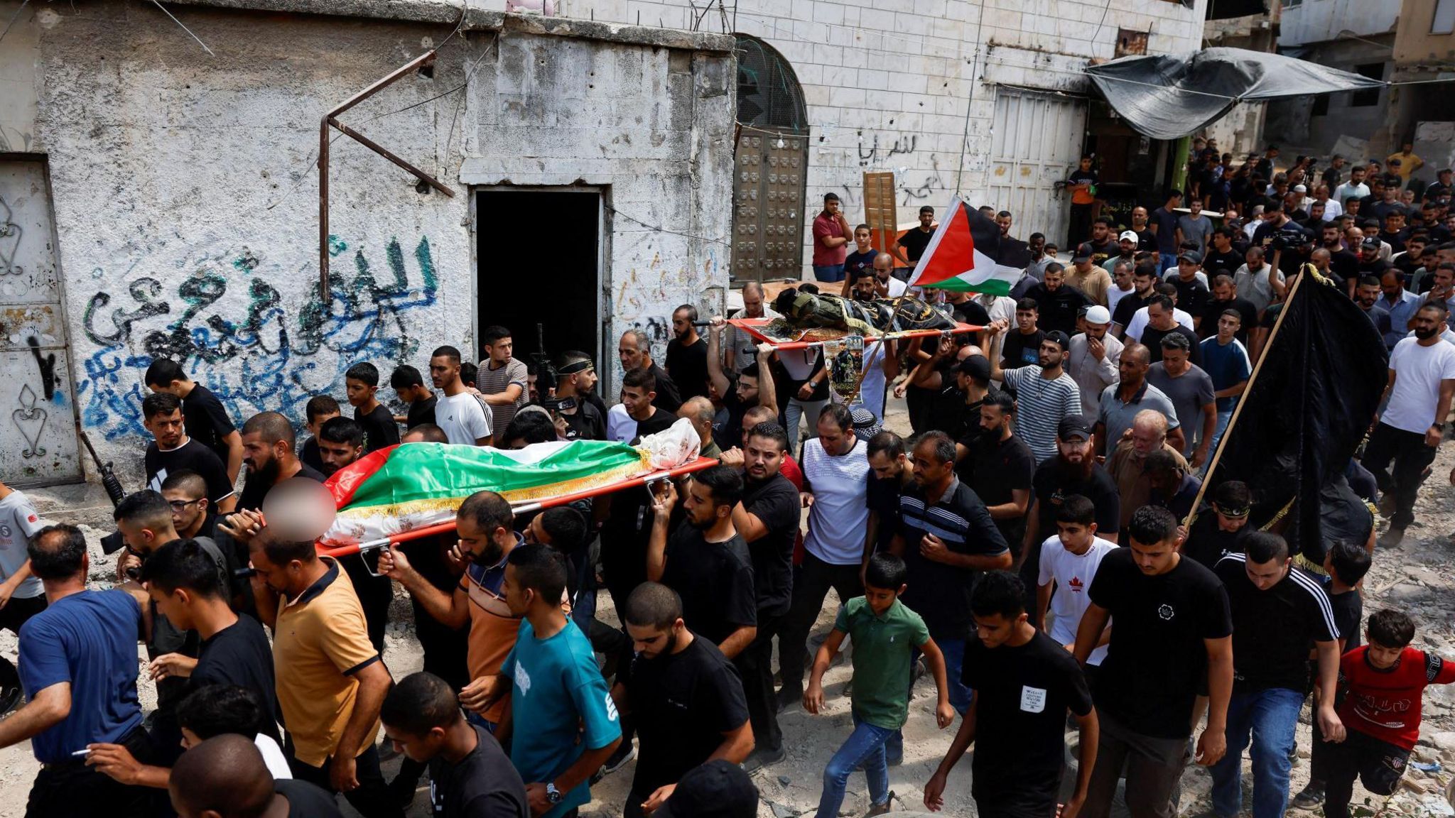 Mourners carry the bodies of Ayed Abu Hajja (left) and a symbolic corpse Mohammed Jaber (right) during a funeral in Nur Shams refugee camp, near Tulkarm, in the occupied West Bank (30 August 2024)