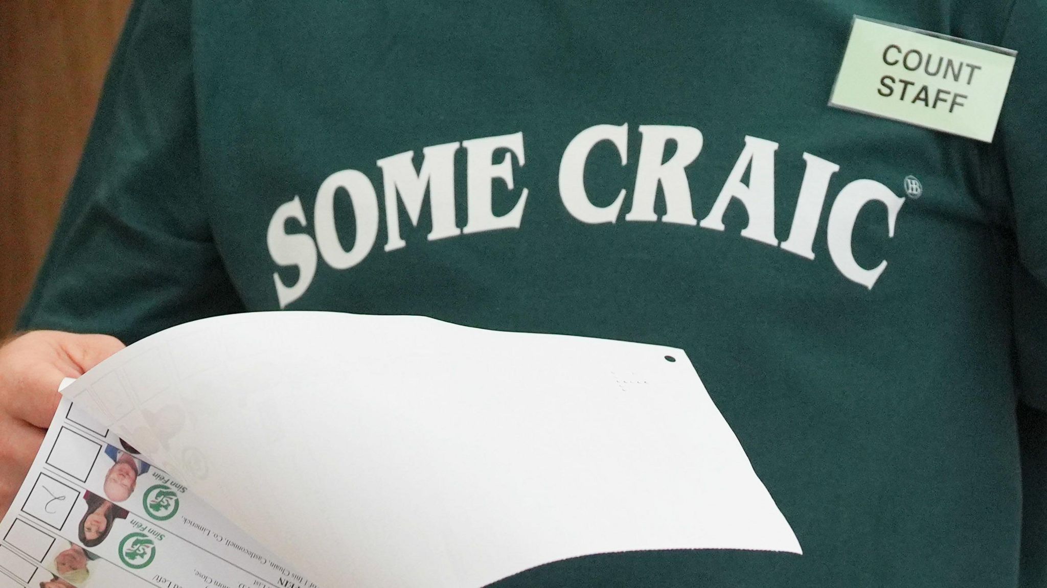 A man wearing a jumper saying 'some craic' tallies ballots