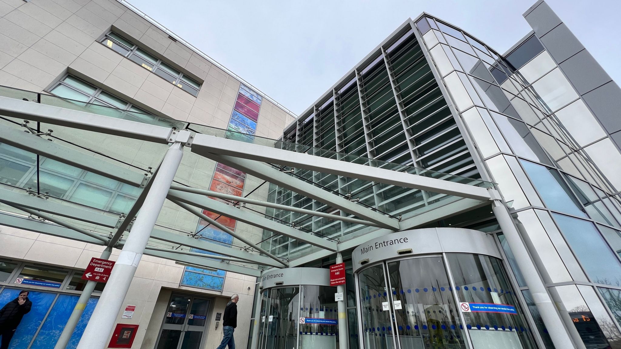 The entrance to Broomfield Hospital, a glass fronted building with revolving doors. 