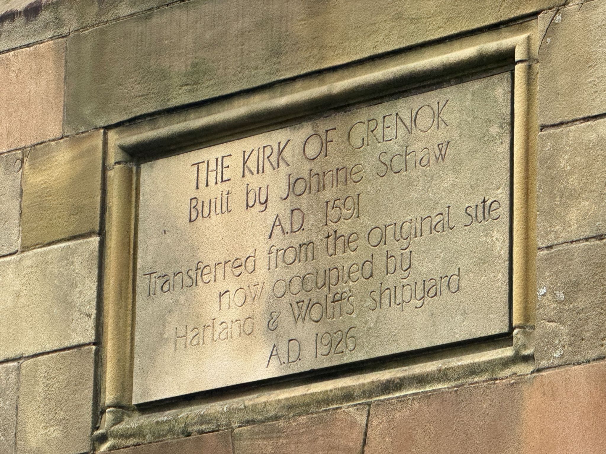 Plaque detailing the move to Greenock's Esplanade that reads: 'The Kirk of Grenok Built by Johnne Schaw A.D. 1591. Transferred from the original site now occupied by Harland & Wolffs shipyard A.D. 1926"