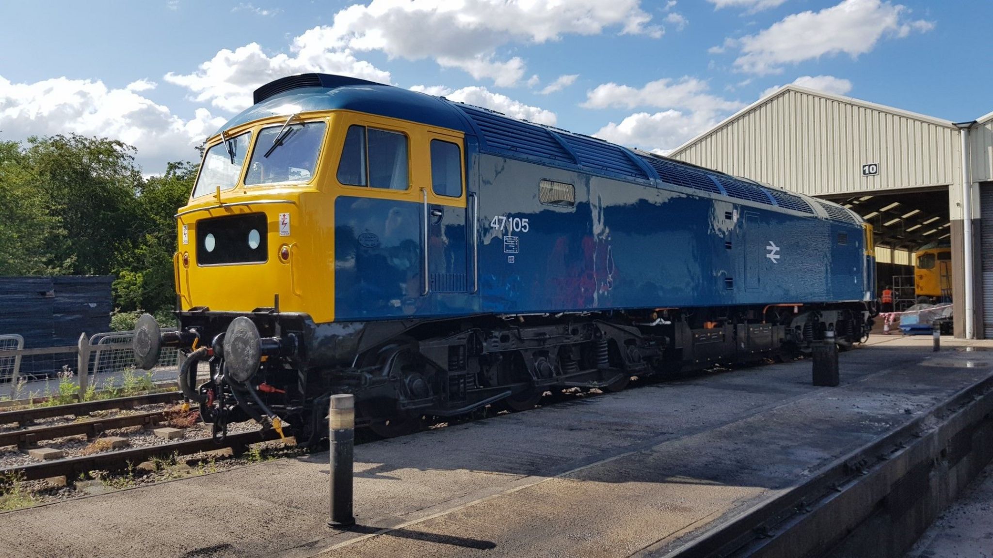 A bright blue and yellow old-fashioned train in a shed.