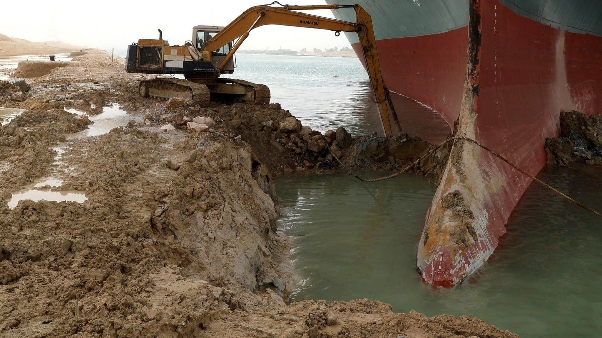 A digger removes sand and mud from the bow of the Ever Given, which ran aground in Egypt's Suez Canal (25 March 2021)
