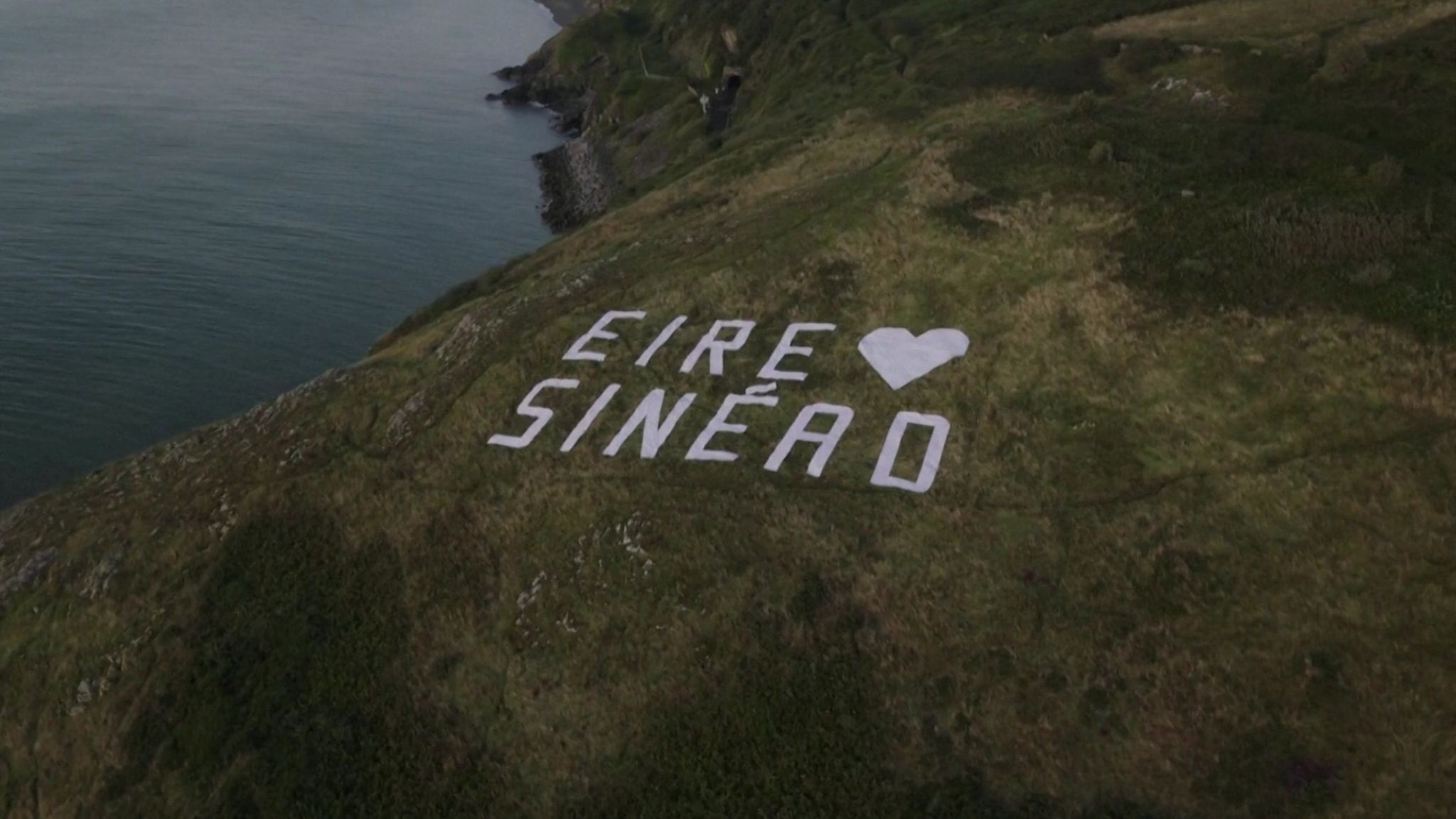 White lettering spells out "Eire loves Sinéad" on the top of a cliff close to Bray