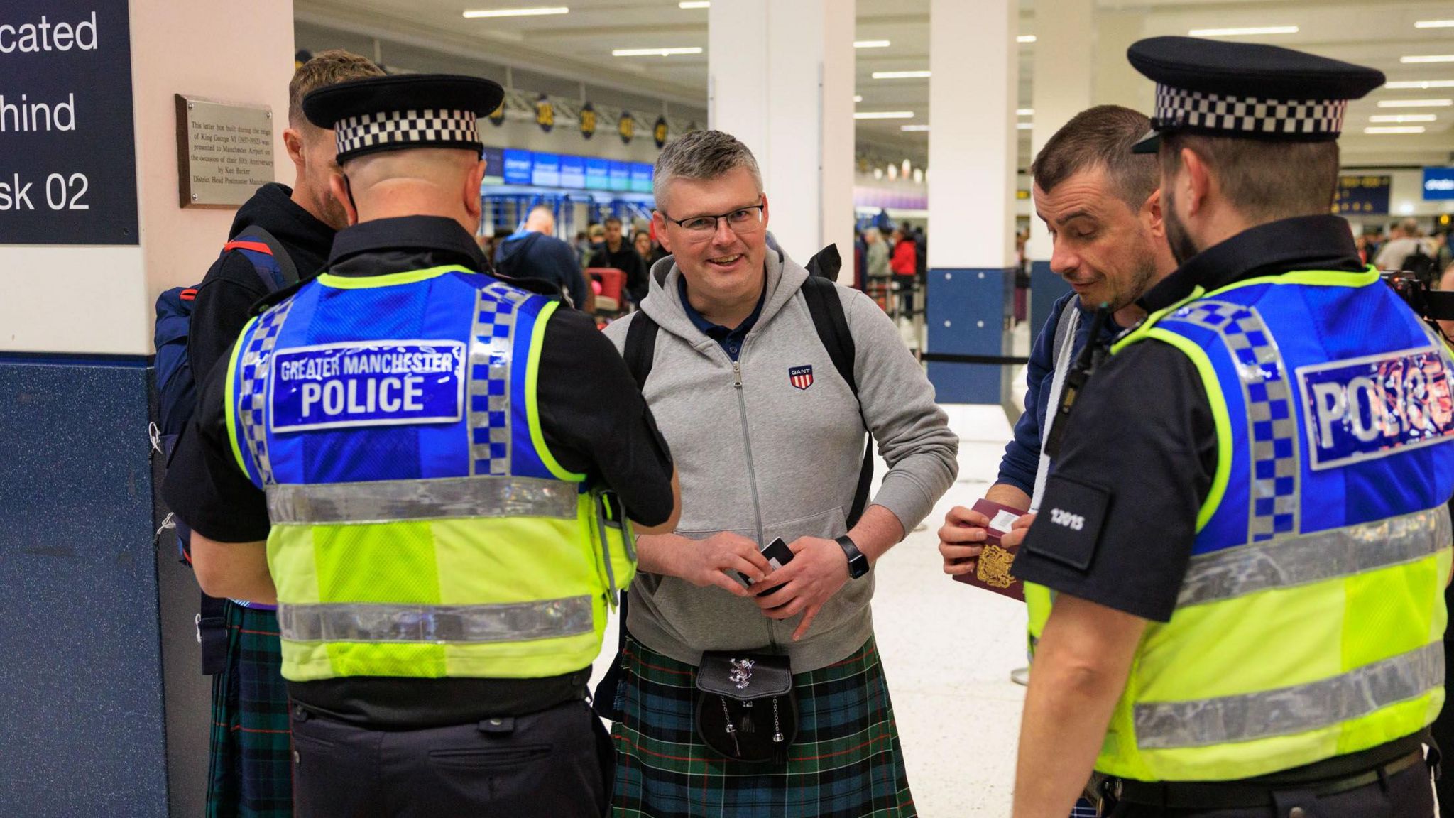 Greater Manchester Police speak to a Scotland fan at Manchester Airport