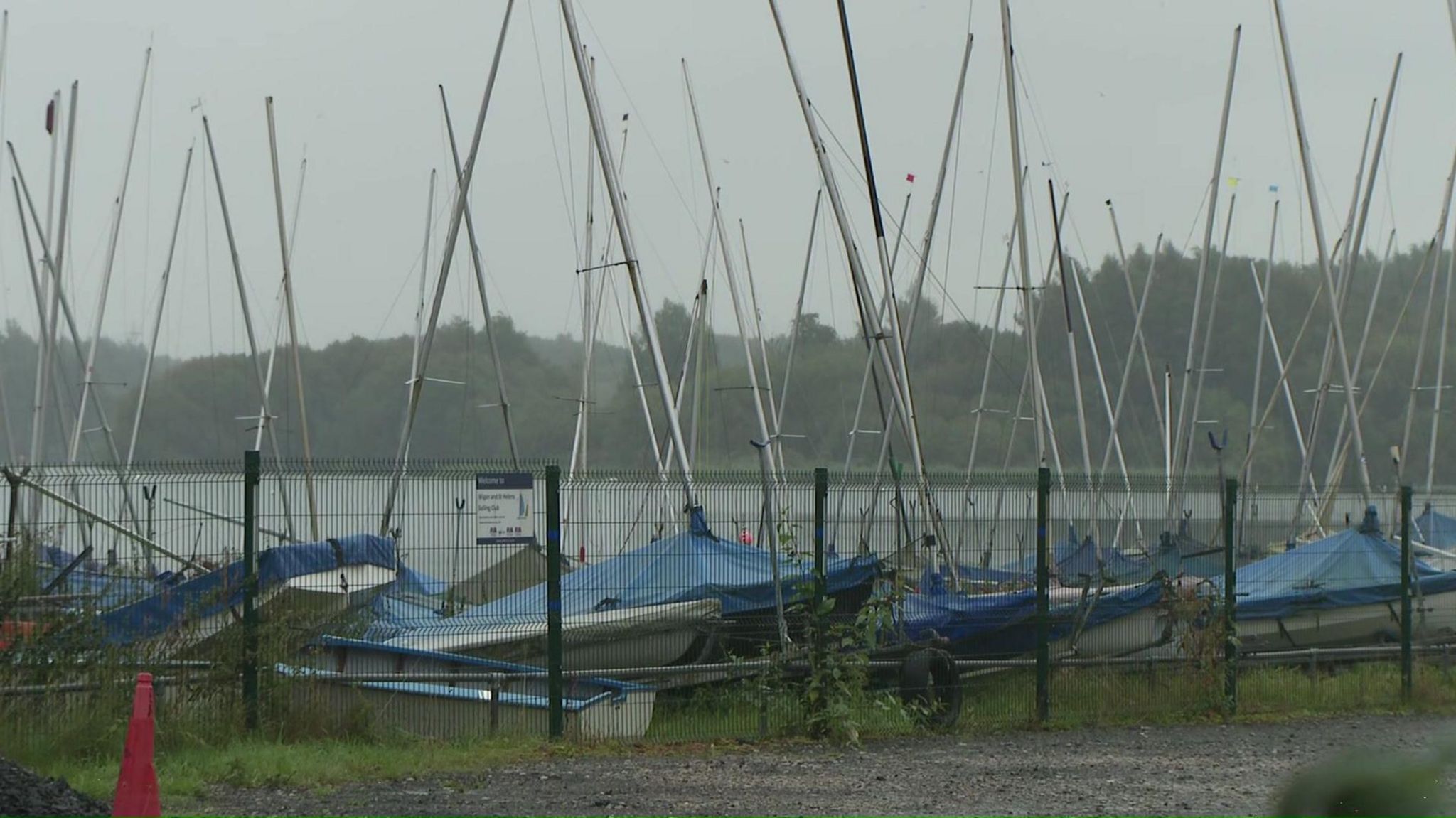 Dinghies behind a fence by the lake's activity centre