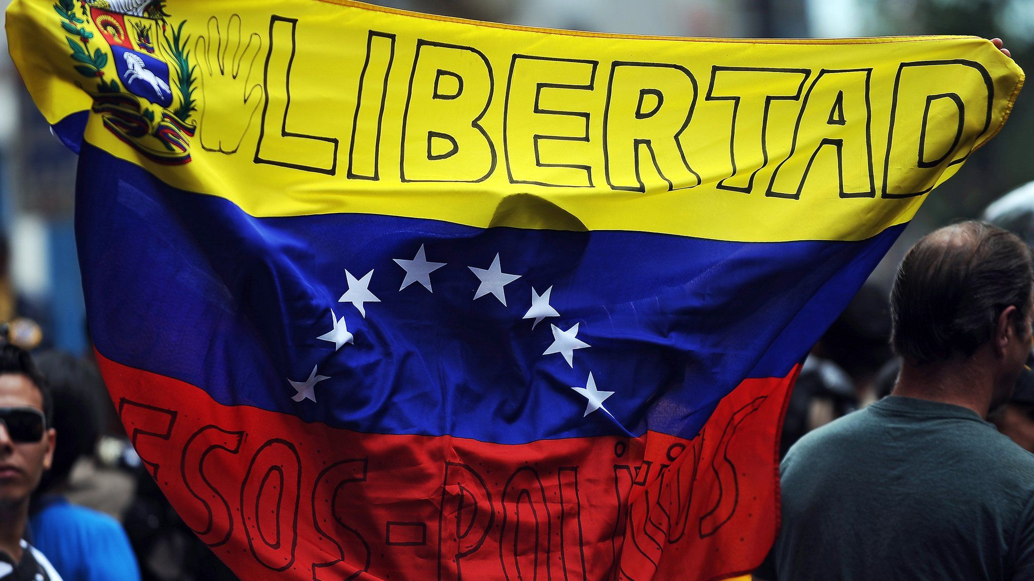 A man waves a Venezuelan flag reading 'Freedom' on it outside of the National Assembly building in Caracas