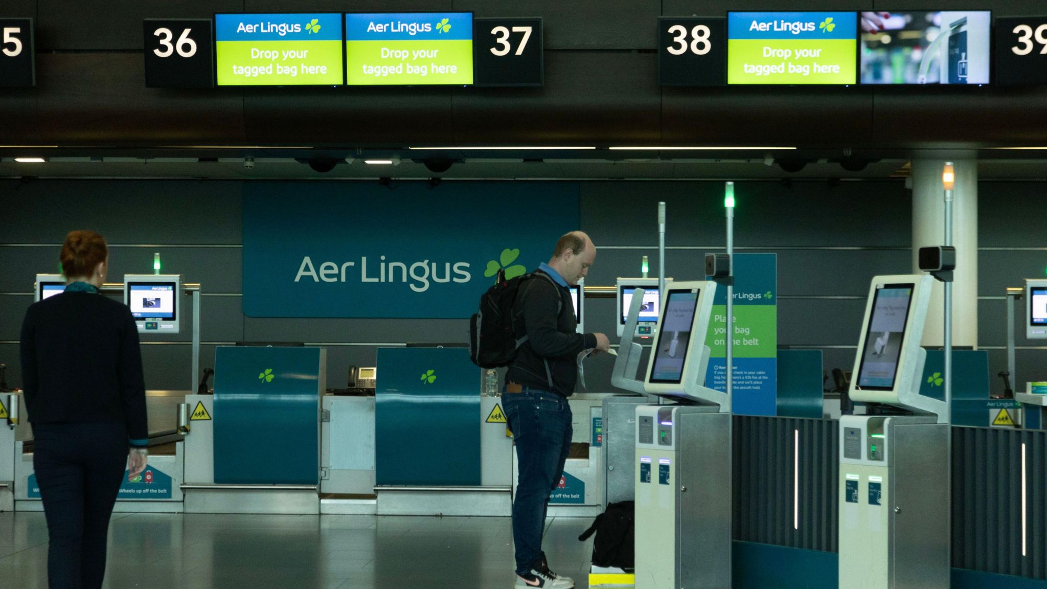 One passenger and one staff member in a near empty Aer Lingus Check-in Desk area at Dublin Airport 