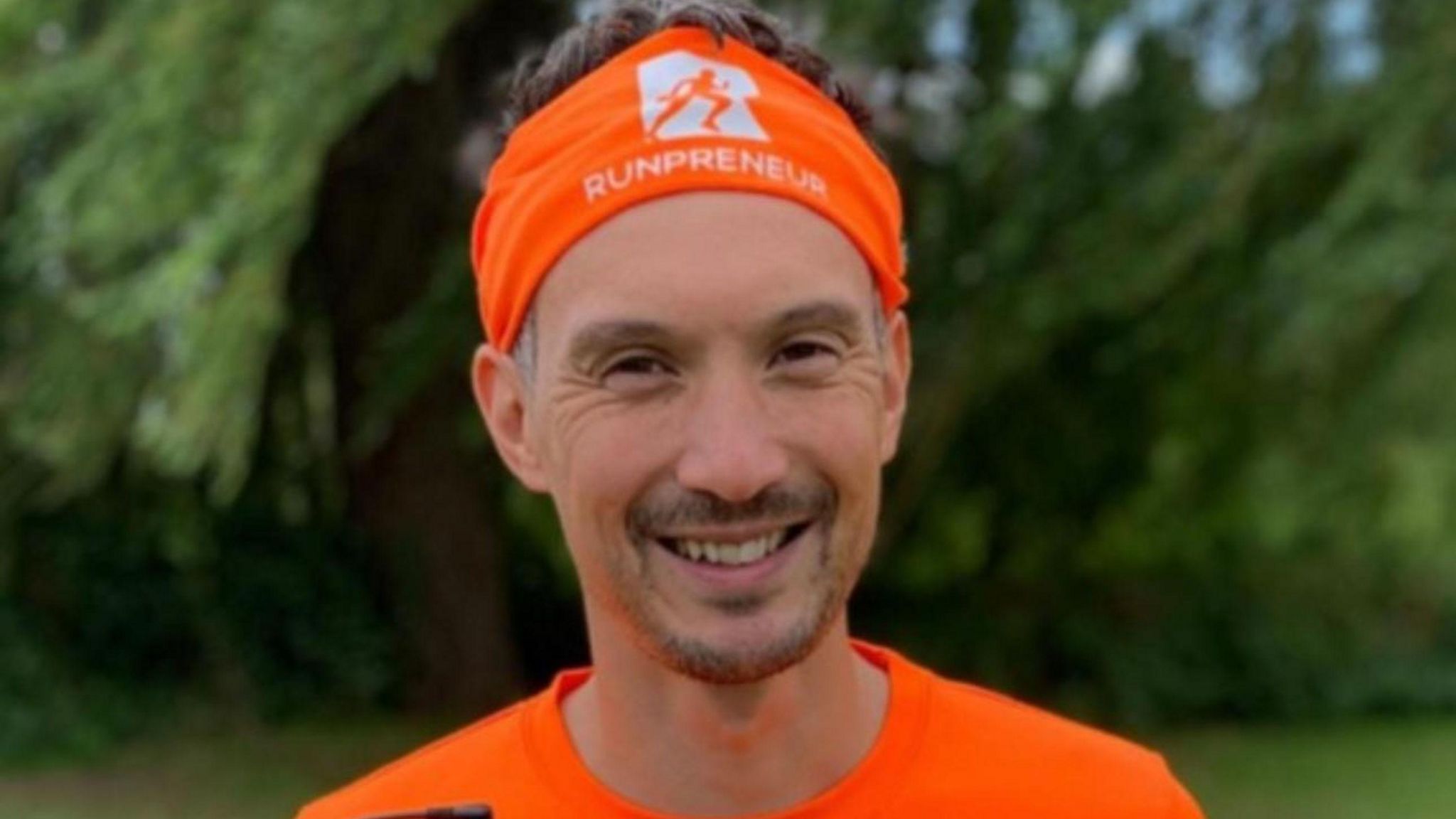 Kevin Brittain with small brown beard wearing an orange top and headband