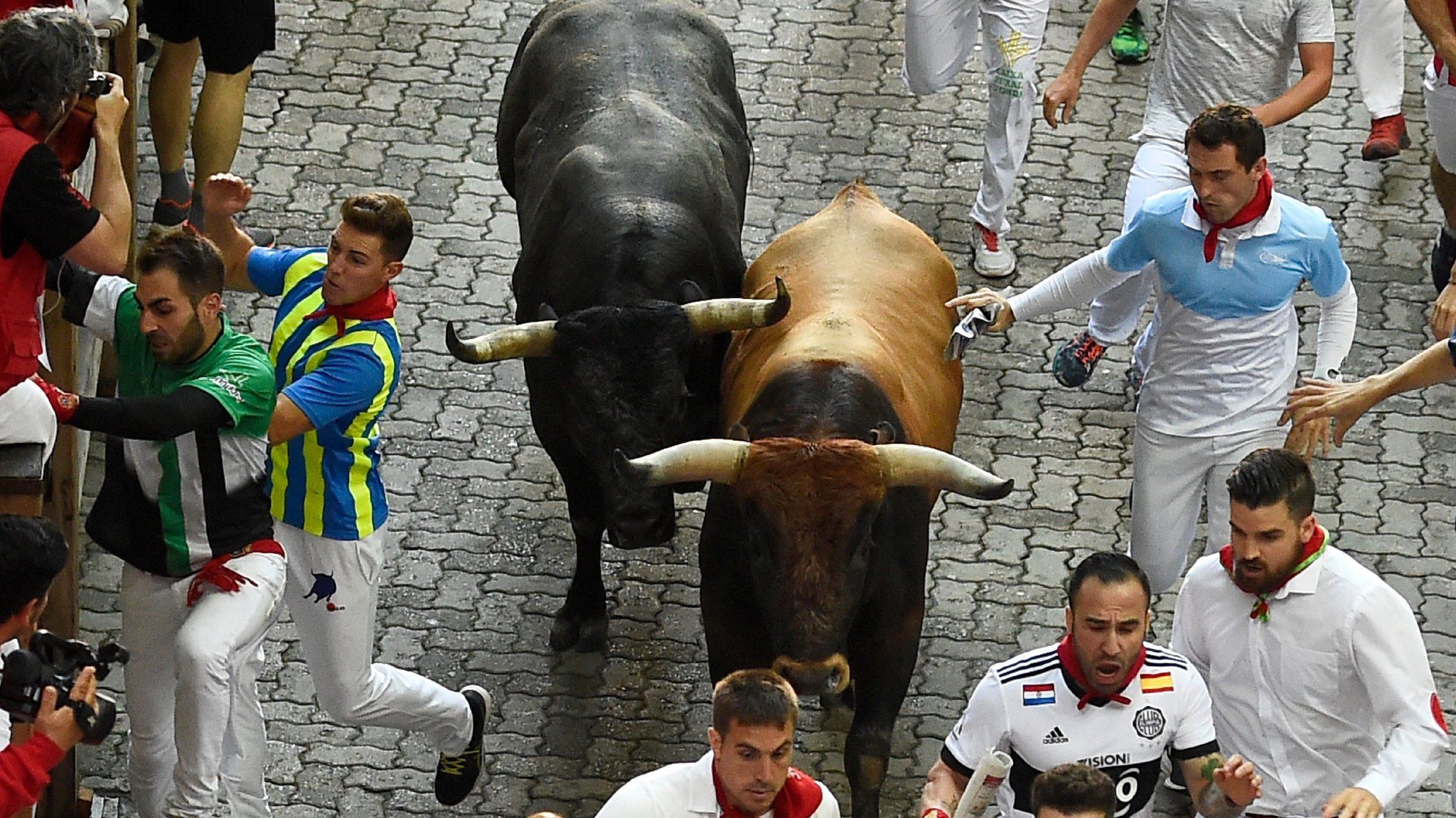 Participants run next to bulls on the last bull run of the San Fermin festival in Pamplona, northern Spain, on 14 July 2018