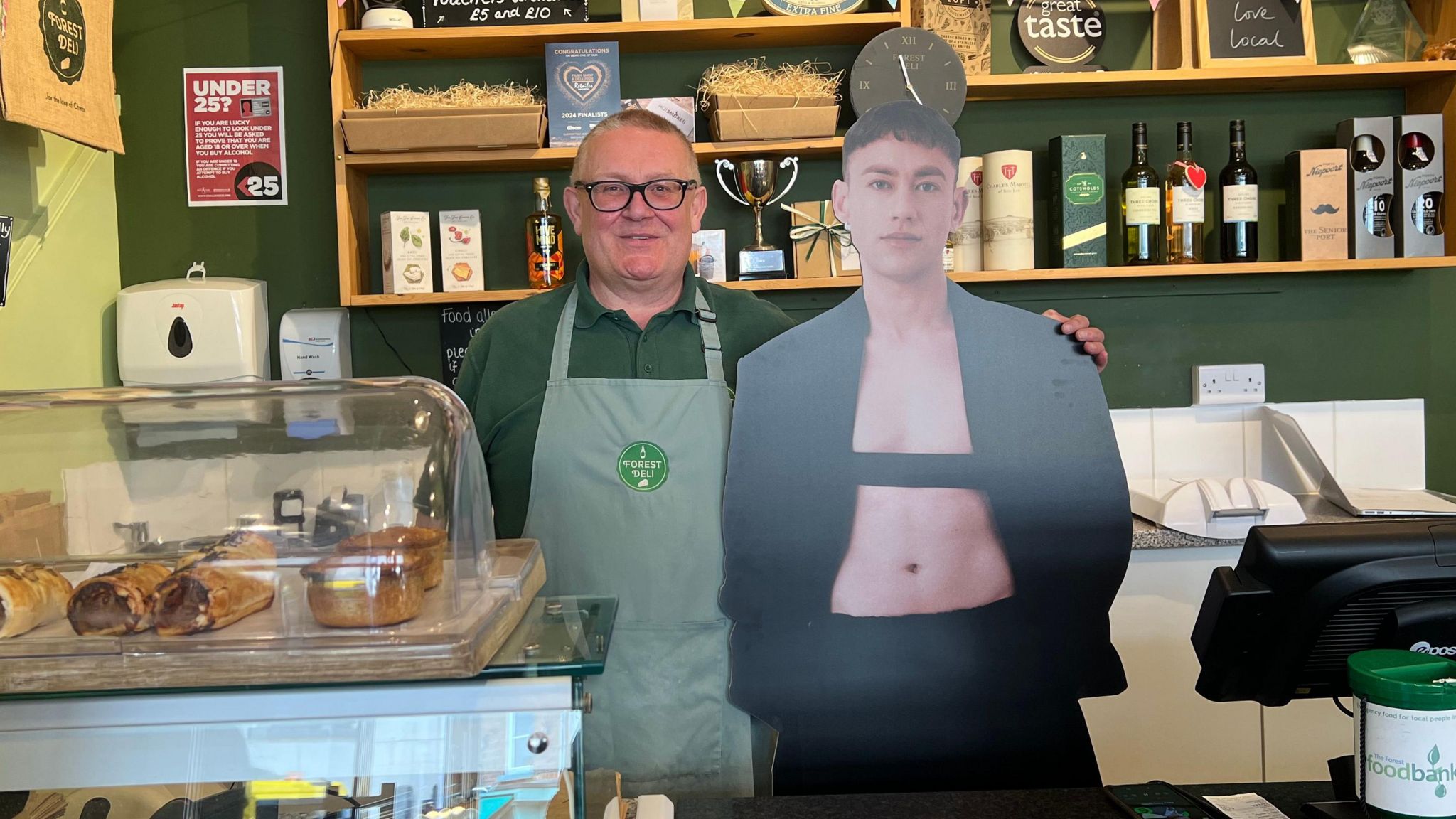 A Forest Deli worker posing with Olly Alexander behind the deli counter