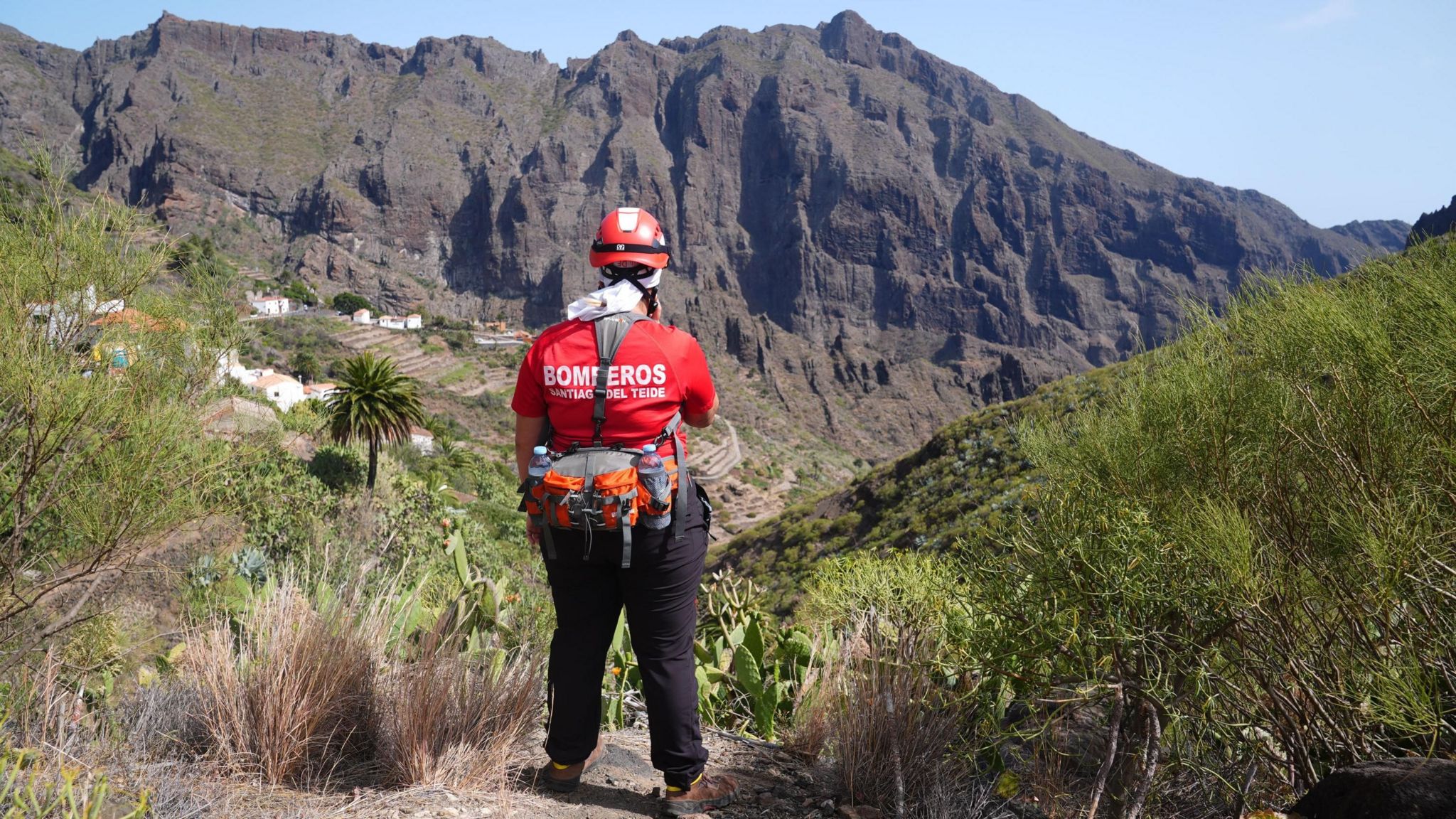 A Spanish rescue worker looking into a valley, a mountain is in the distance