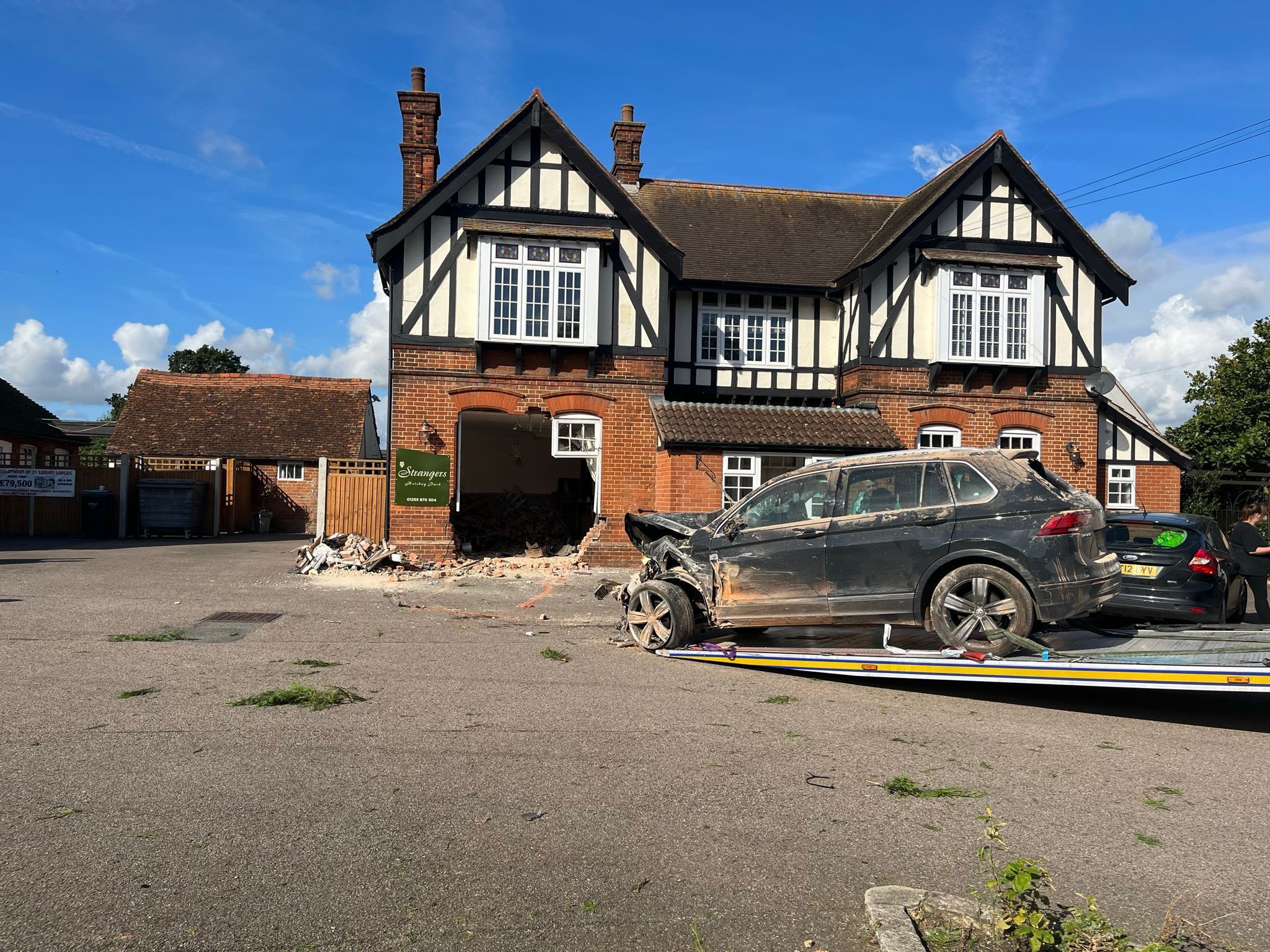 A damaged car outside the pub, which has a big hole in a wall, after the crash