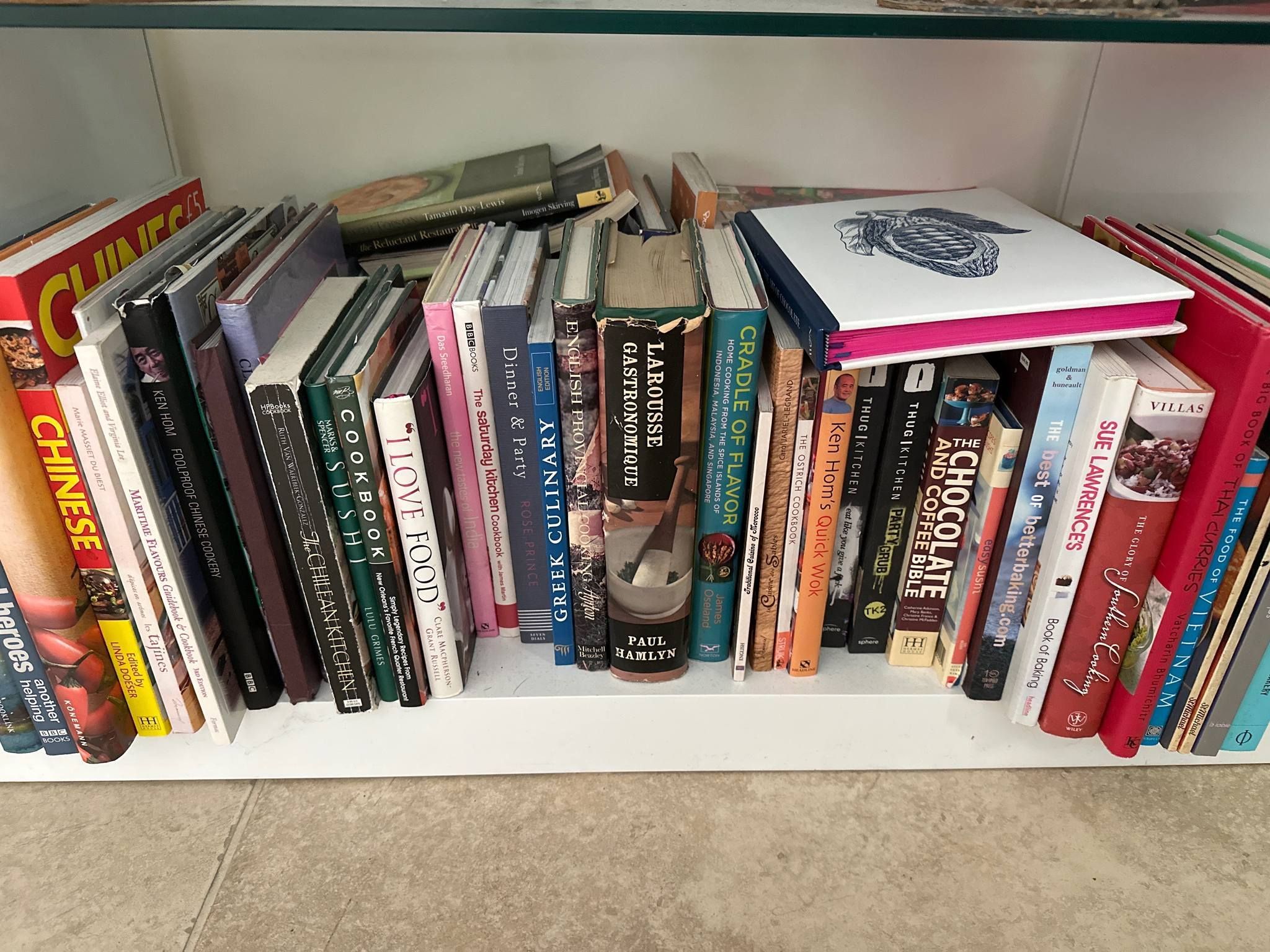 A shelf full of cookbooks. Titles include: 'The Chocolate and Coffee Bible' and 'The Big Book of Thai Curries'