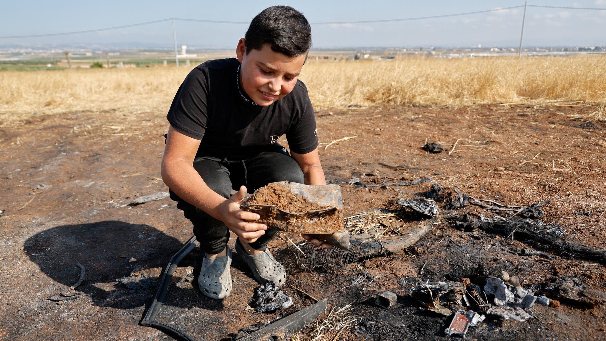 A boy looks at a metal fragment following an Israeli drone strike in the northern West Bank that killed three Palestinian militants (22 June 2023)