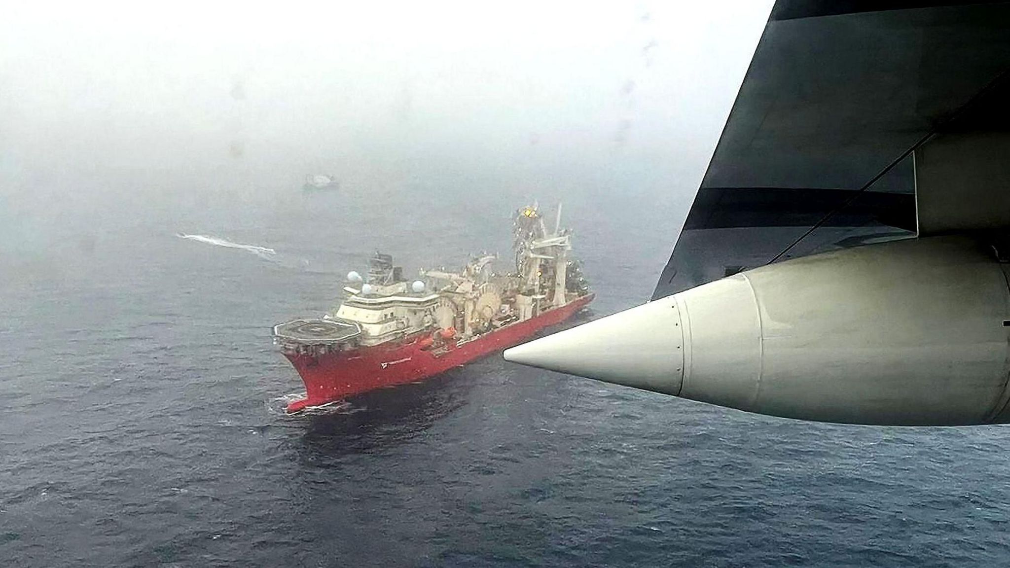 Photo taken from an airplane flying over the sea, searching for the Titan. A number of boats are sailing in the sea below.