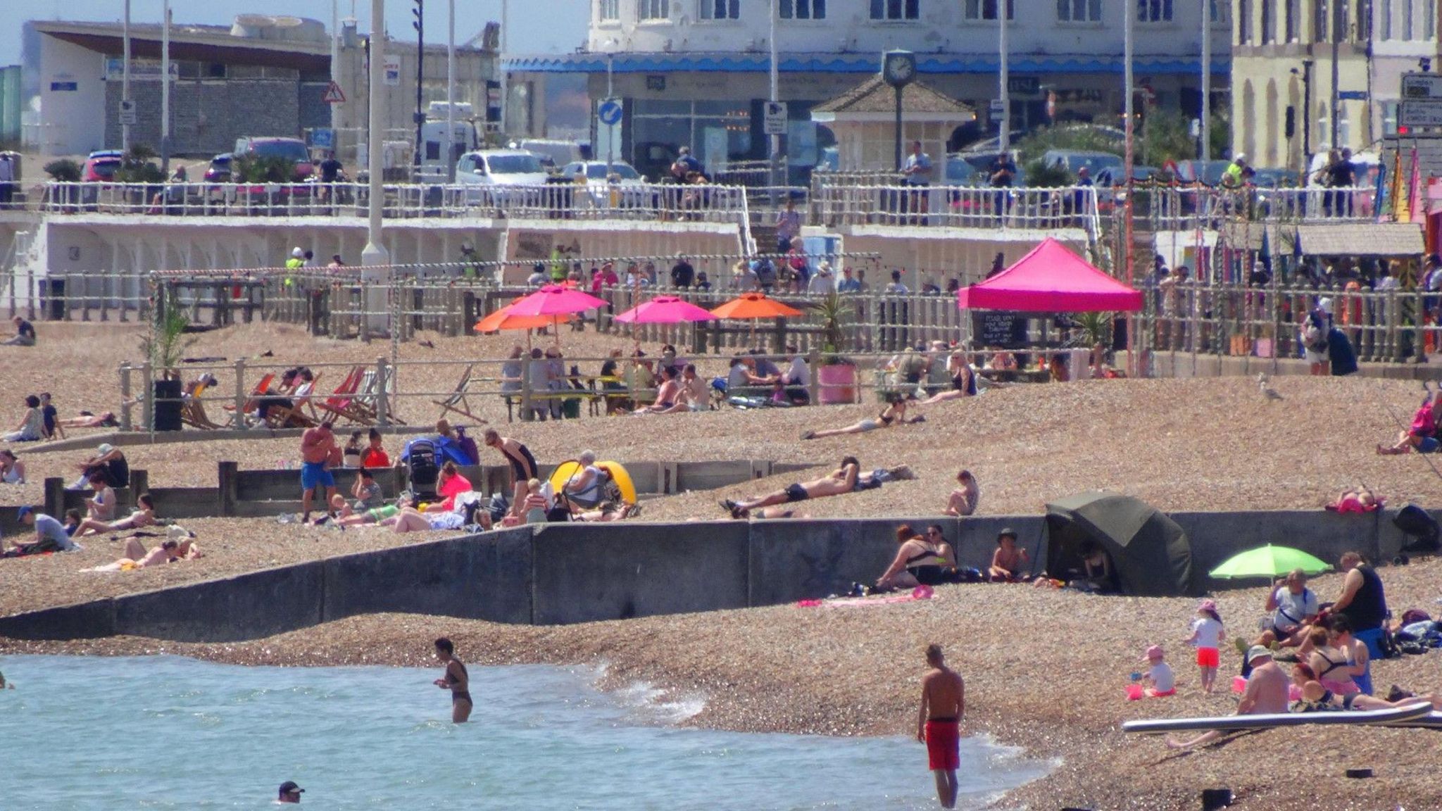 Groups of people relaxing on a sunny beach with the sea just visible in the foreground