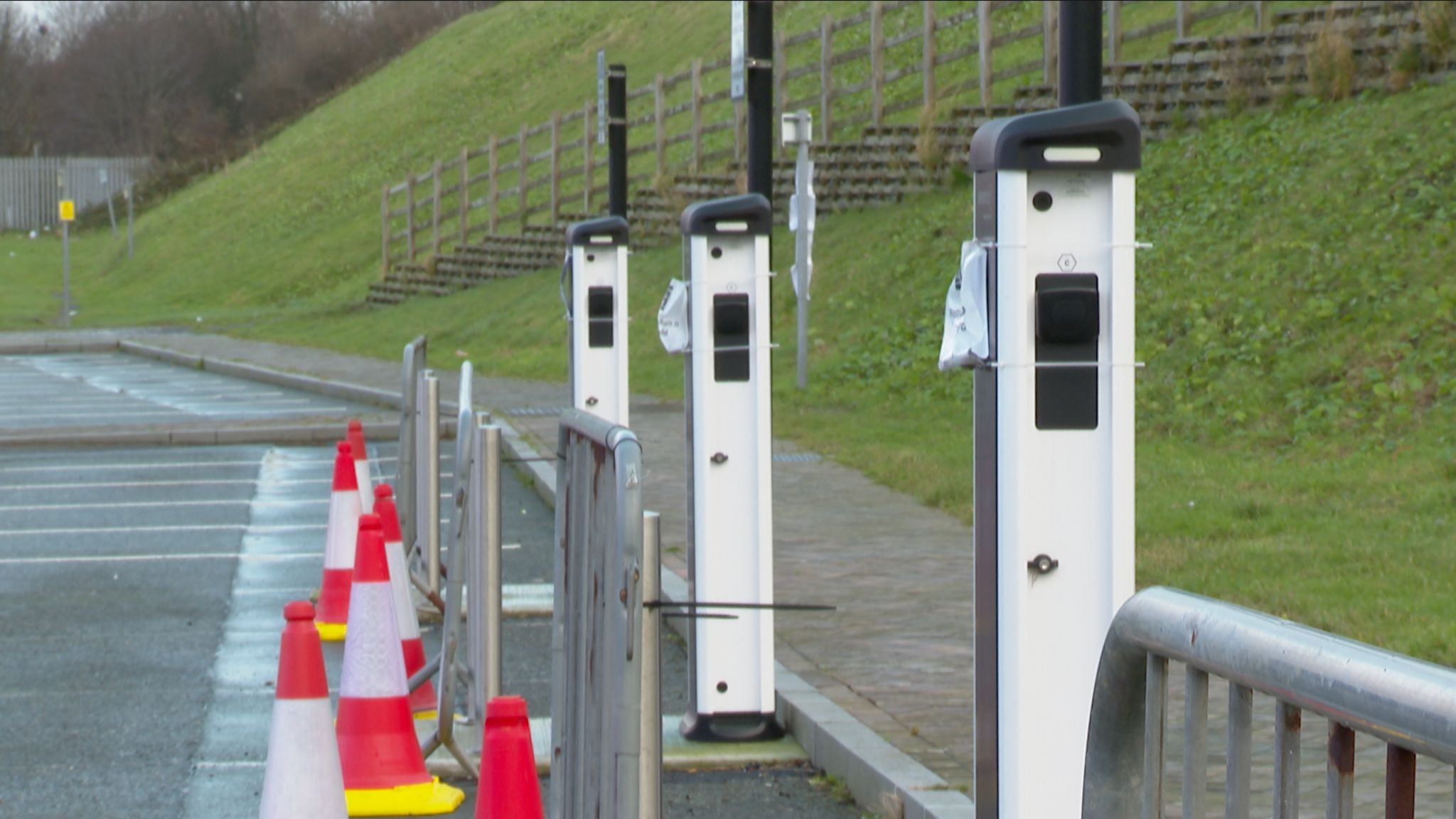 Unconnected chargers at Victoria Dock Shell car park in Caernarfon, coned and barriers in front, with "out of use" signs pinned to the charging points