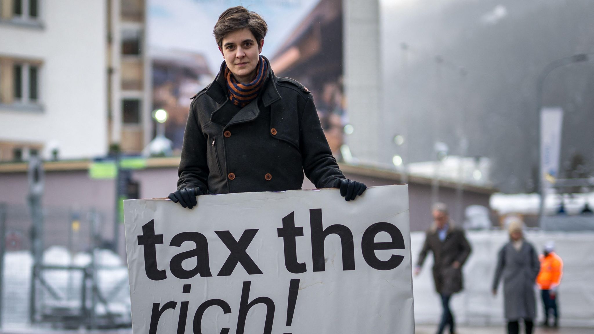 Austrian Marlene Engelhorn, who inherited from her family who owns the Germany's chemical giant BASF, poses with a placard reading "Tax the rich!" at the entrance of the Congress center on the opening of the annual meeting of the World Economic Forum (WEF) in Davos, on January 15, 2024