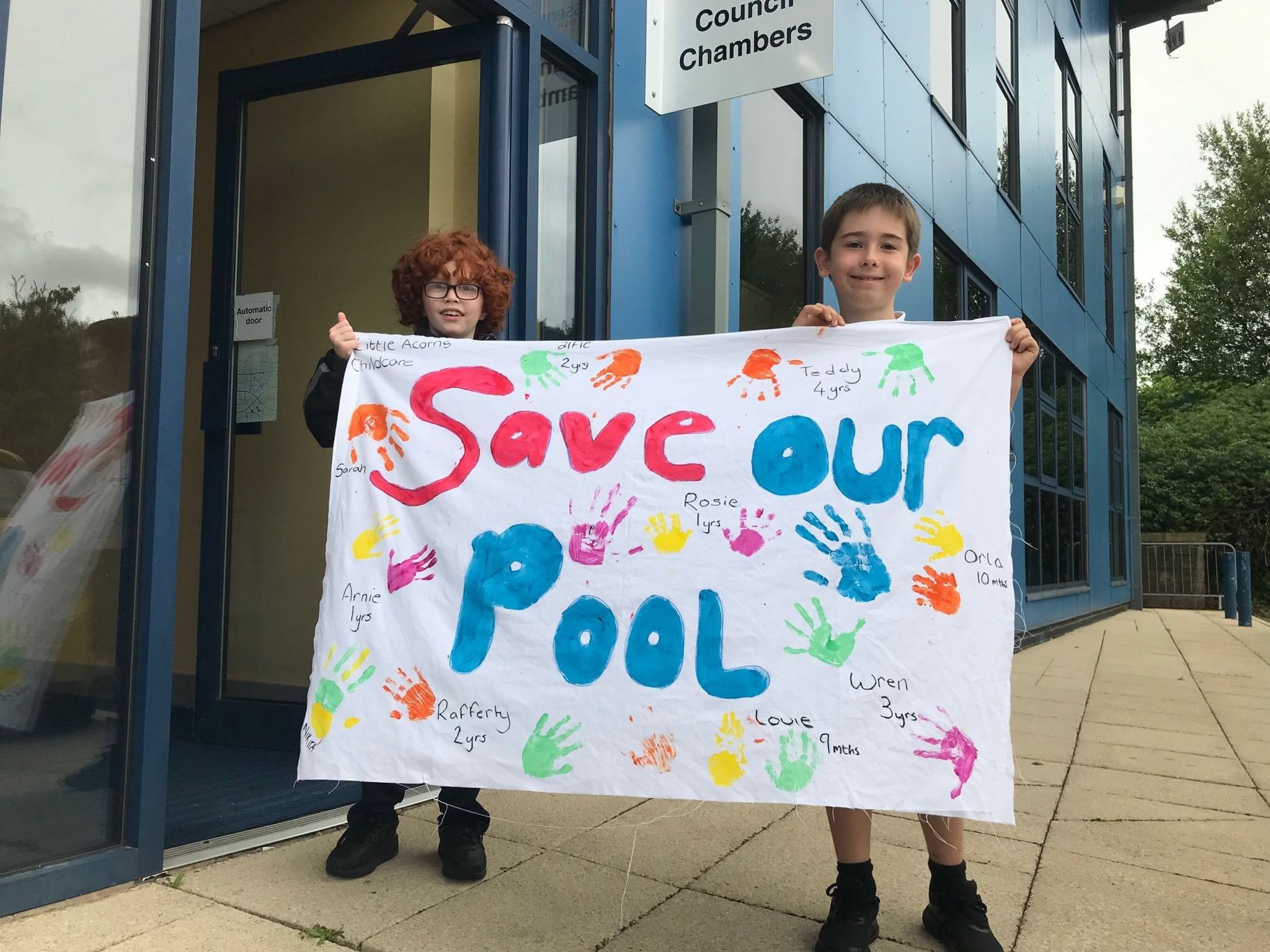 Two children hold up a 'Save our Pool' sign