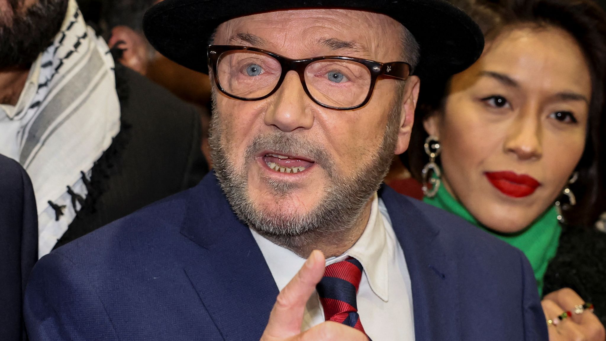 Politician George Galloway, after winning the Rochdale by-election in February 2024. He is wagging a finger and wears his trademark black hat. 