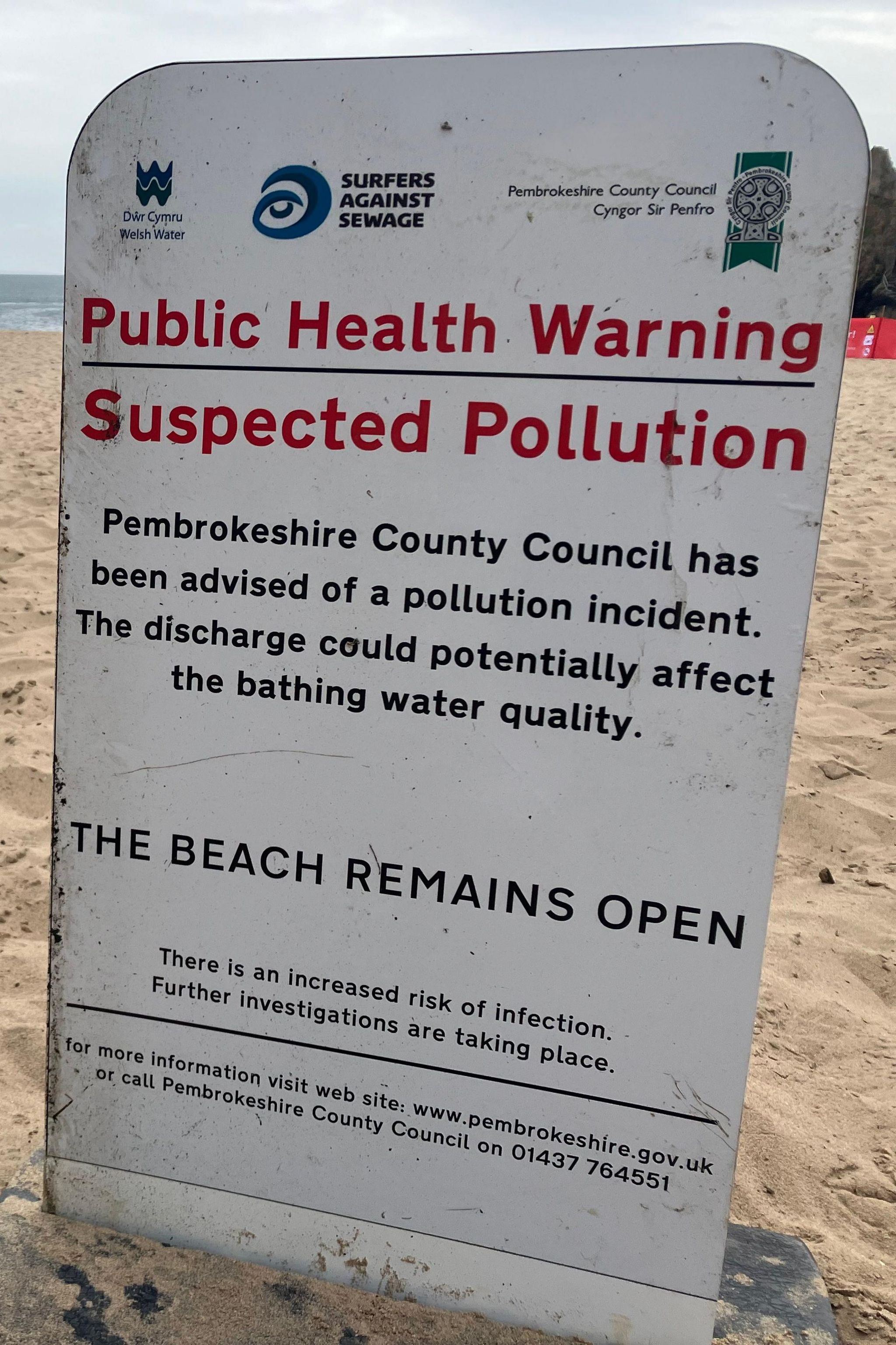 Sign on a beach that says suspected pollution