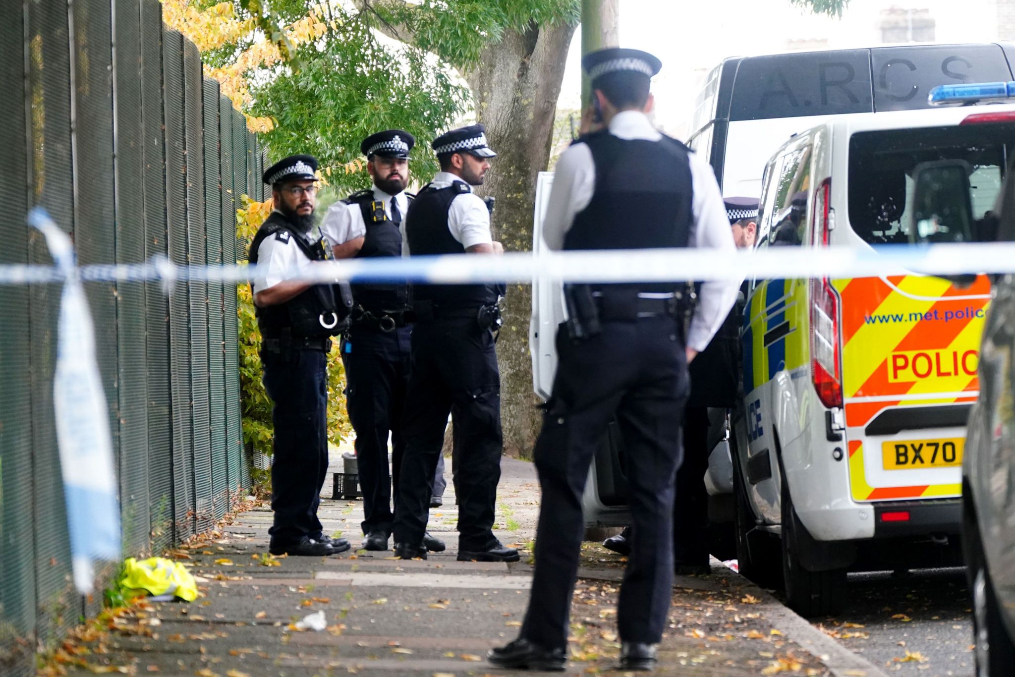 Officers standing behind police cordon at the scene of the fatal stabbing in Enfield, London