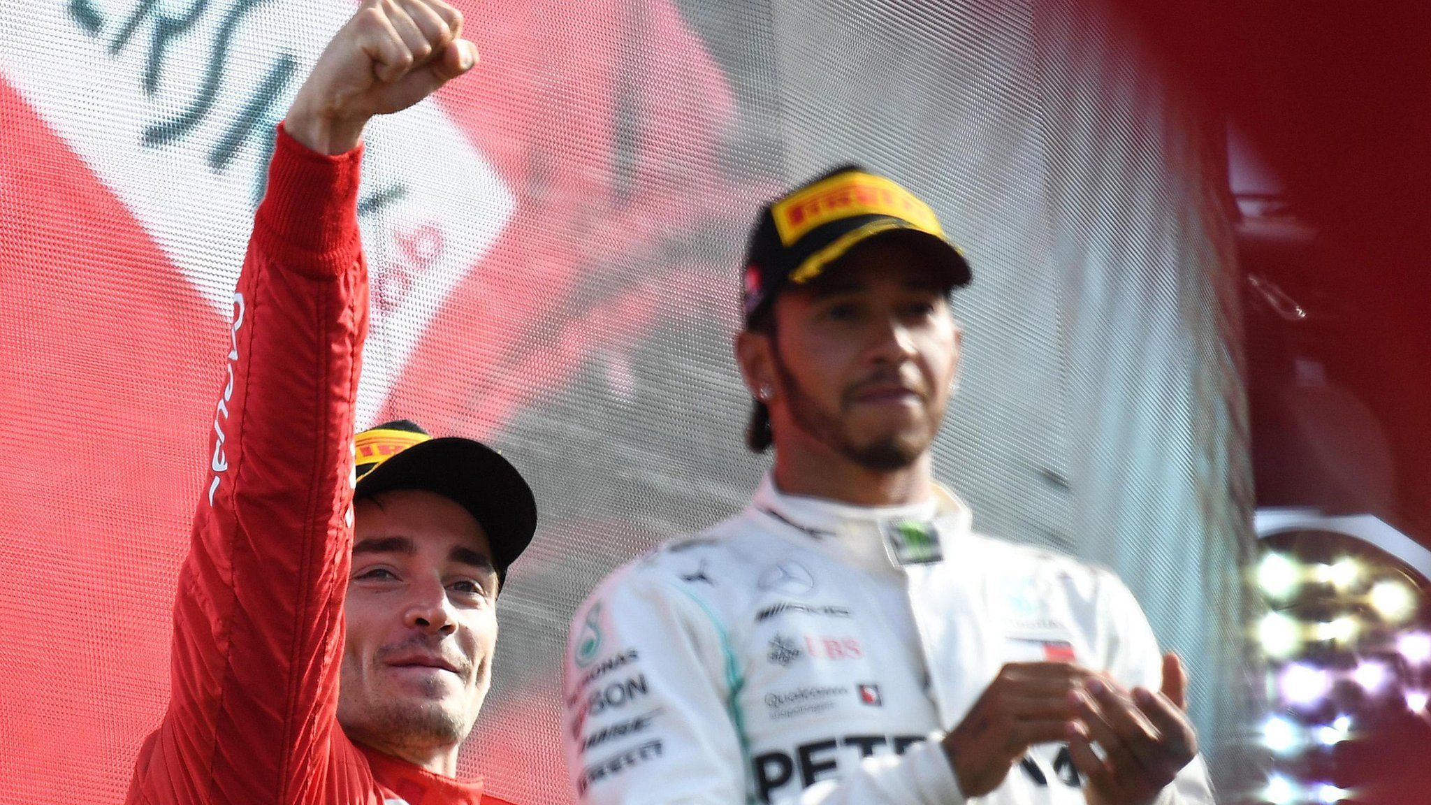 Charles Leclerc celebrates on the podium with Lewis Hamilton