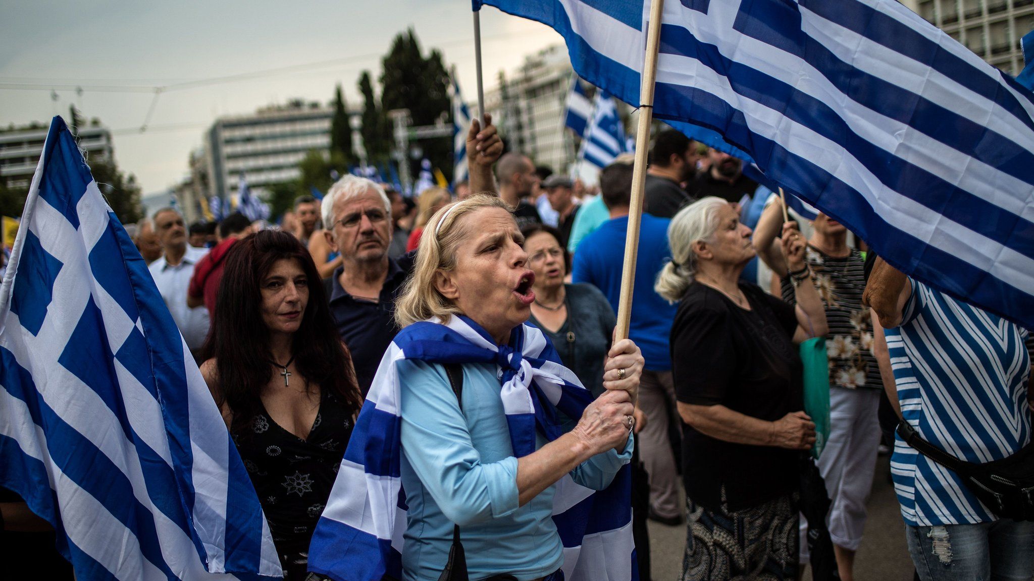 A woman holds a Greek flag during a demonstration in Athens on June 16, 2018 against the agreement reached to resolve a 27-year name row with Macedonia has kicked up a political storm in Greece.