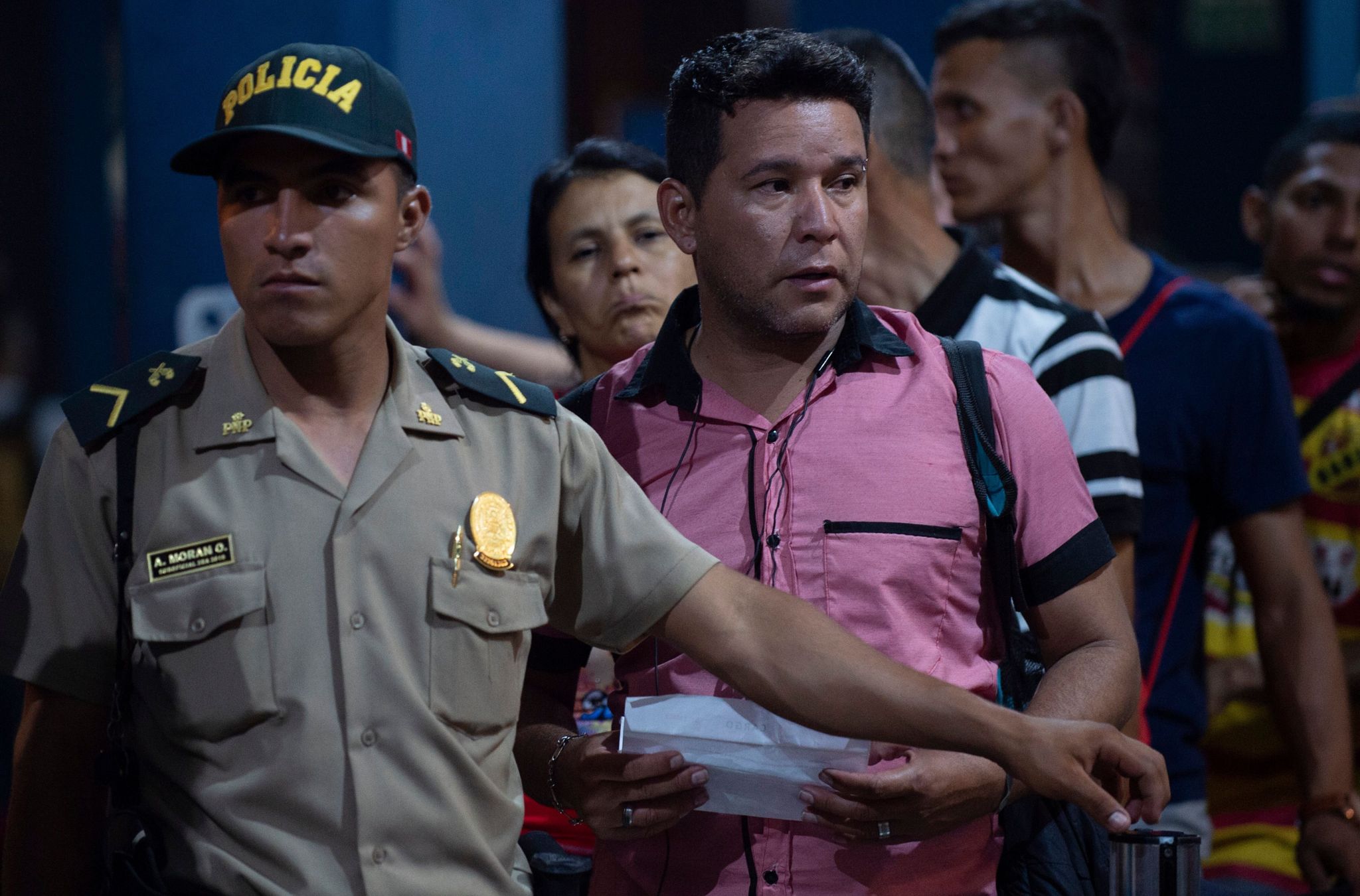 A Peruvian policeman assists Venezuelan citizens waiting in line to get a refugee application at a Peruvian border post at the binational border attention centre (CEBAF) in Tumbes on June 14, 2019.
