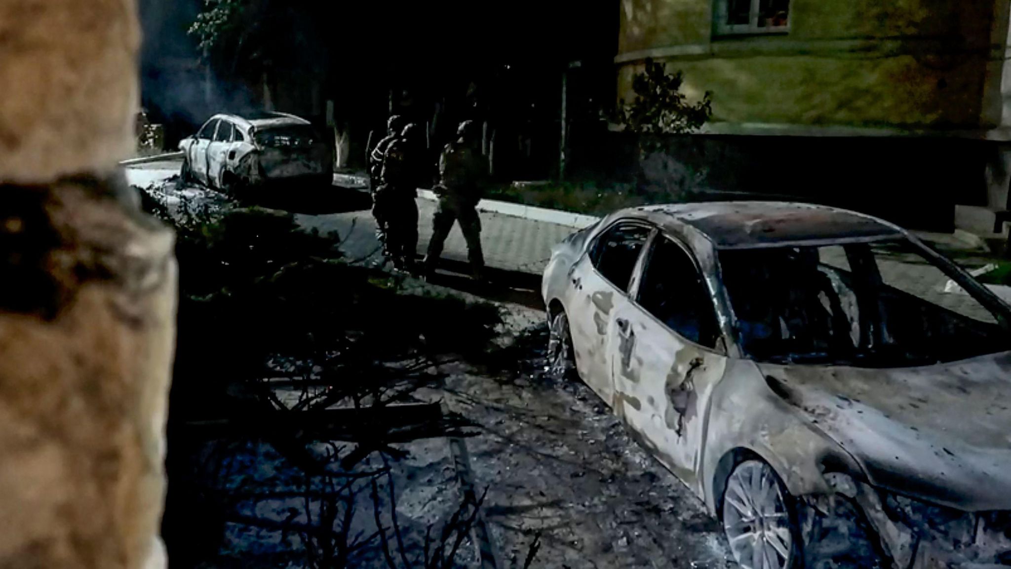 Russian Federal Security service officers approach a burnt out car following the attack