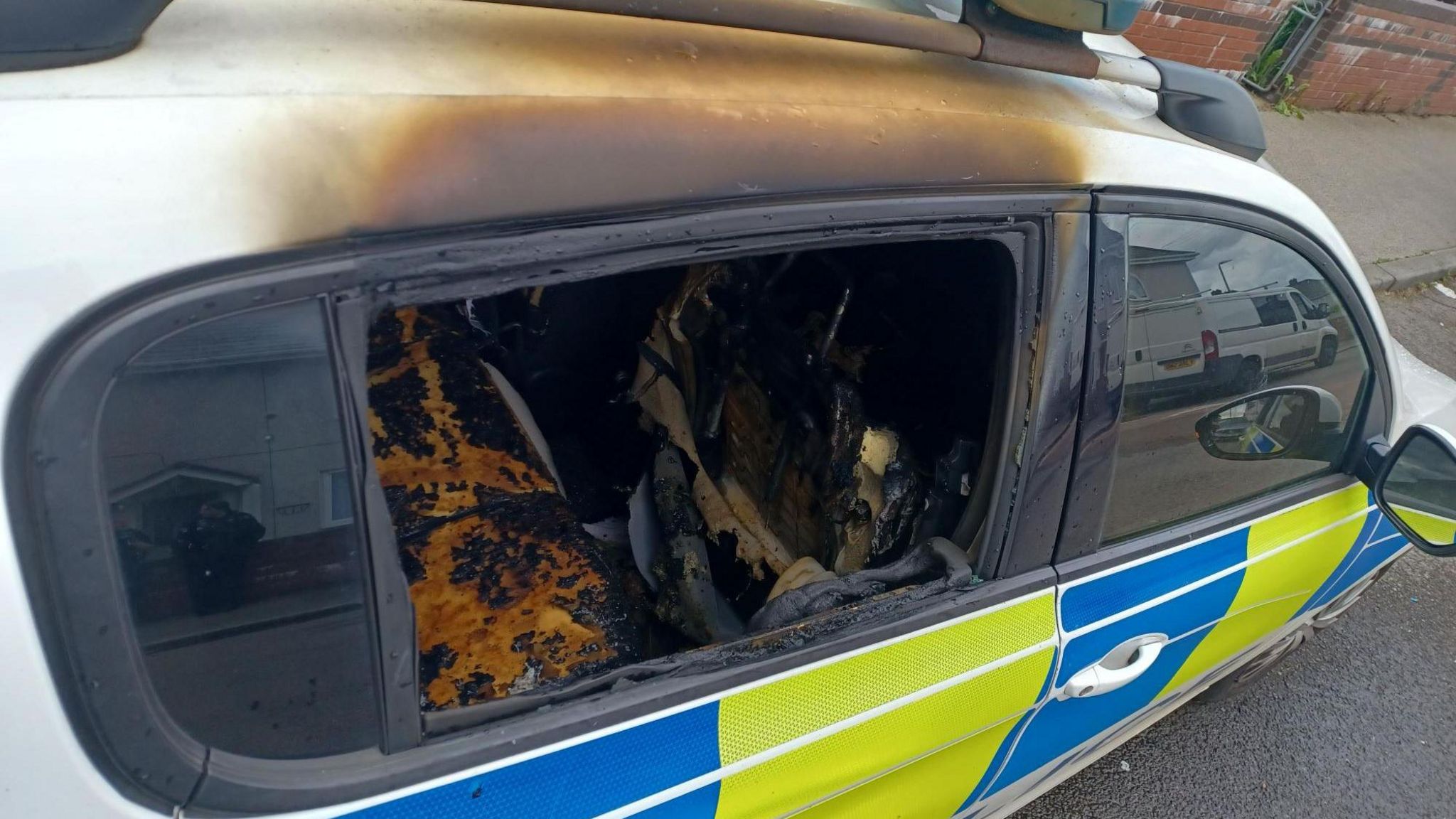 The police car's smashed window and burnt interior