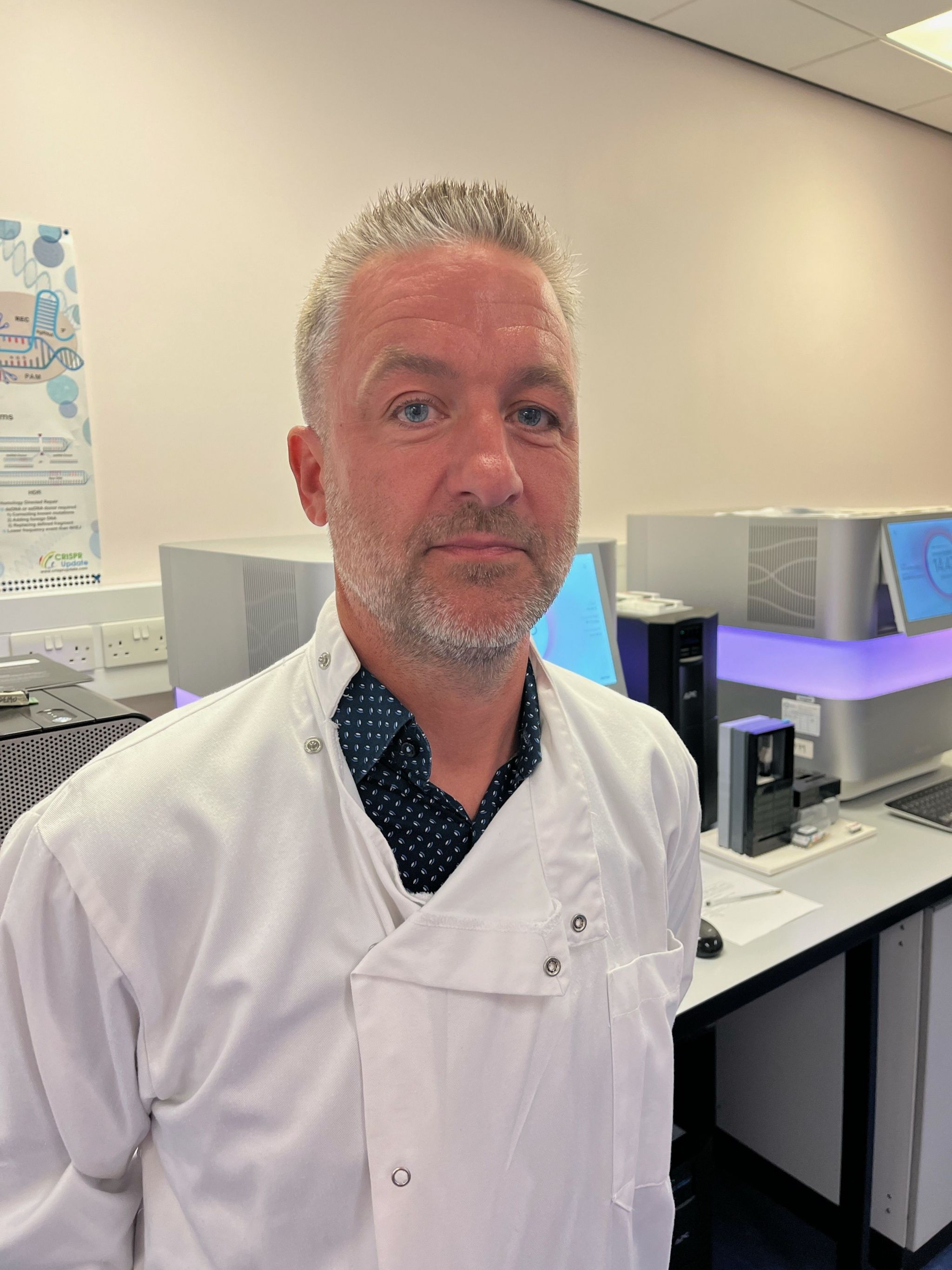 Prof Jim Wilson in his research lab, wearing a white coat