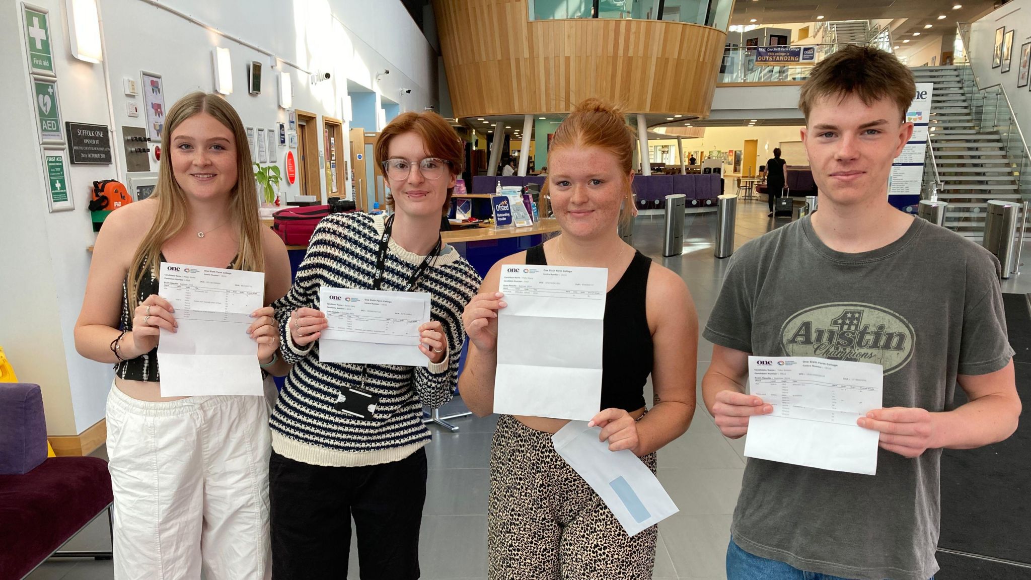 Students Megan Green, Noctis Clark, Molly Moore and Toby Groom stand in  a line, each holding their results in front of them