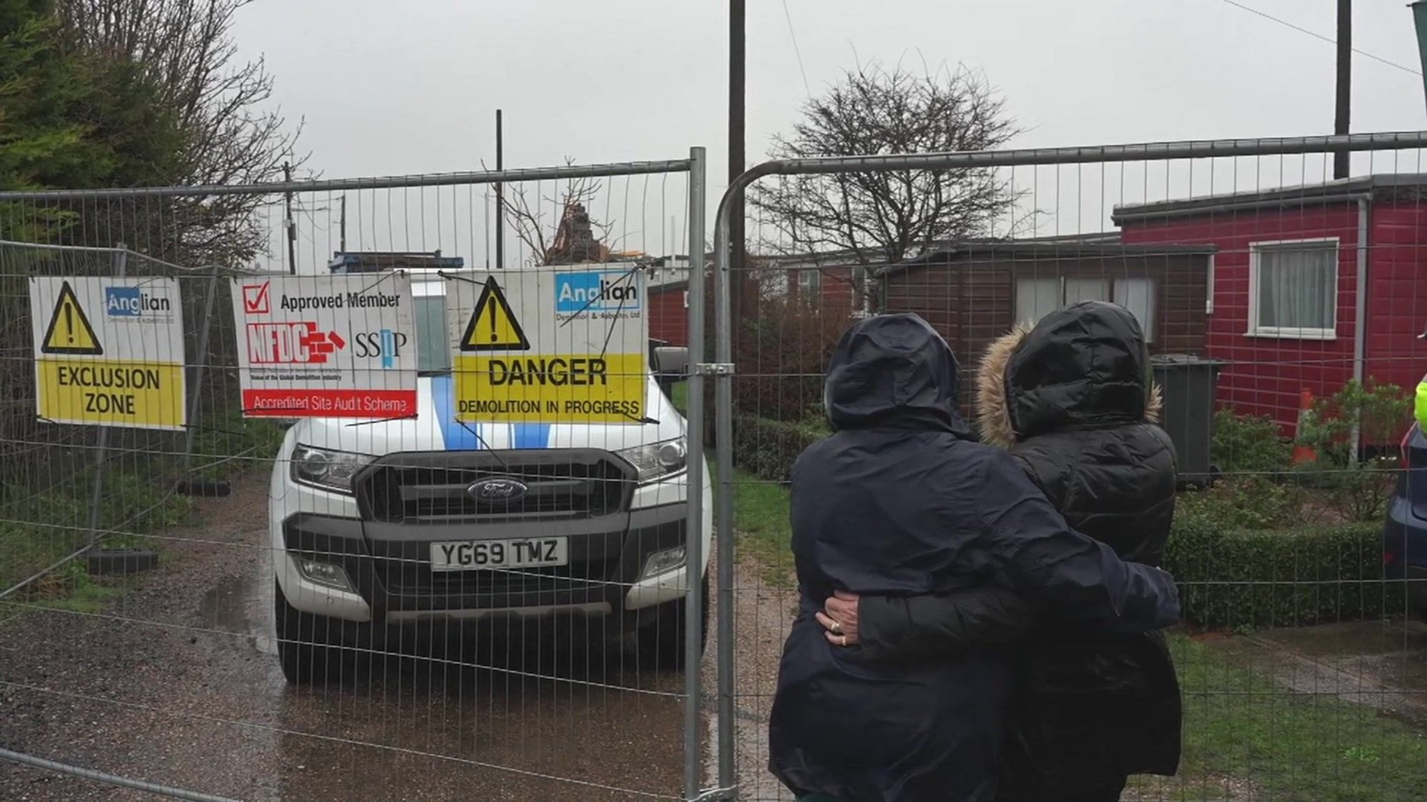 Two people hug as they watch the chalet demolition take place