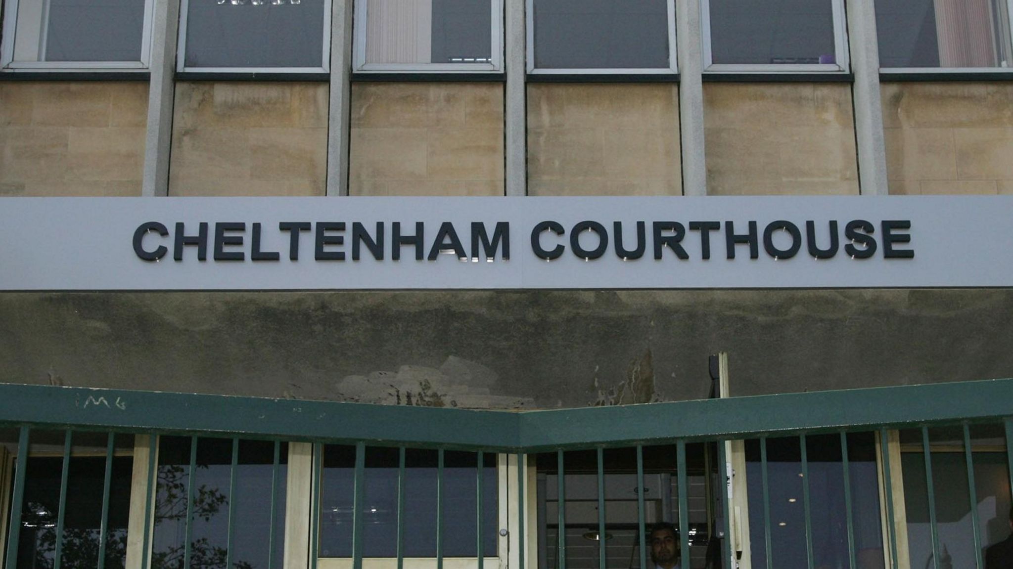 An exterior view of Cheltenham Magistrates Court with a large sign saying "Cheltenham Courthouse" in dark letters on a metallic background