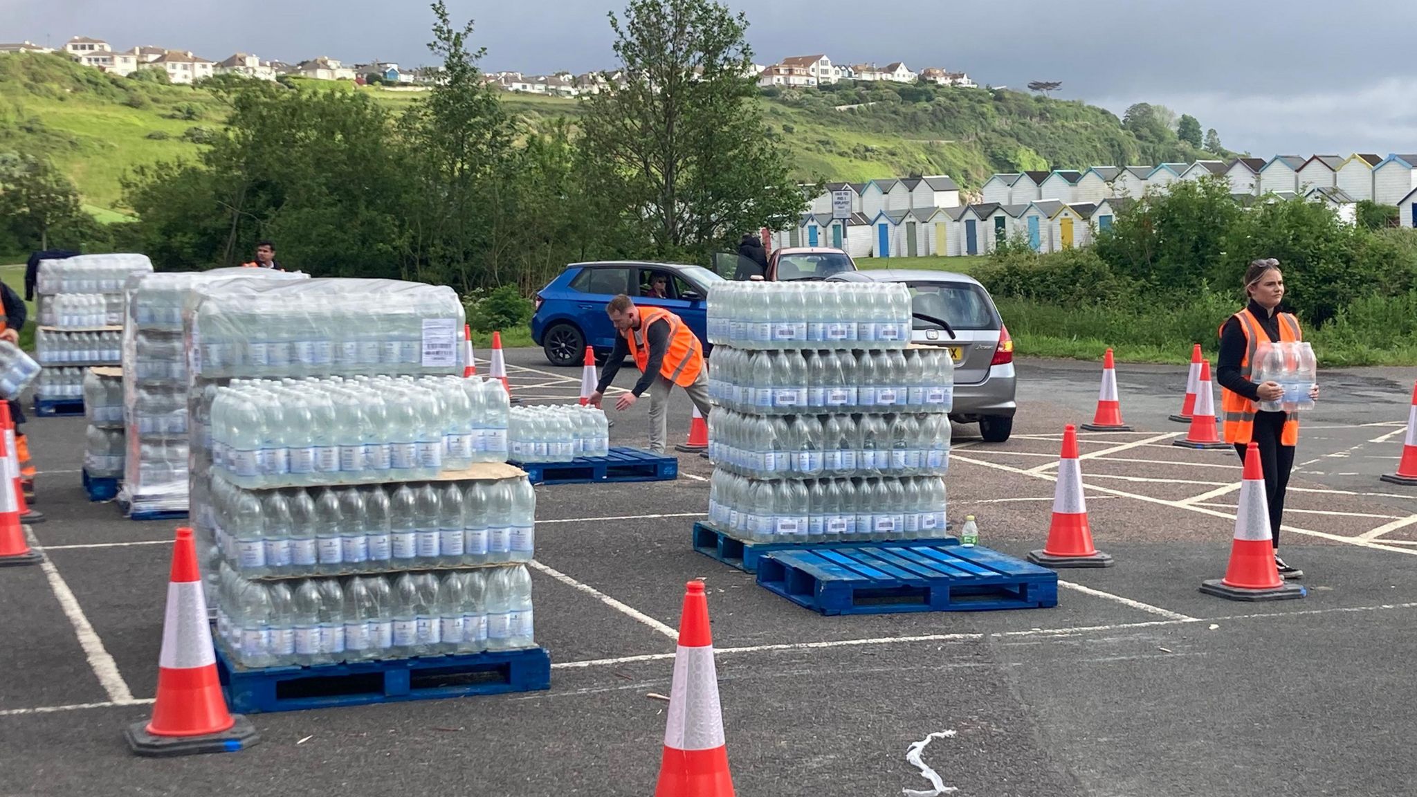 Packs of water bottles stacked on pallets in a car park 