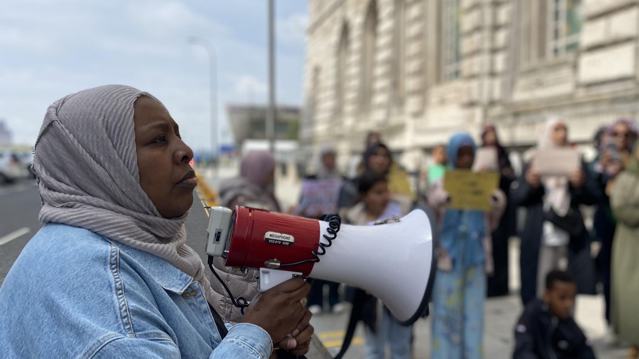 Amina Ismail addressing the crowd with a megaphone