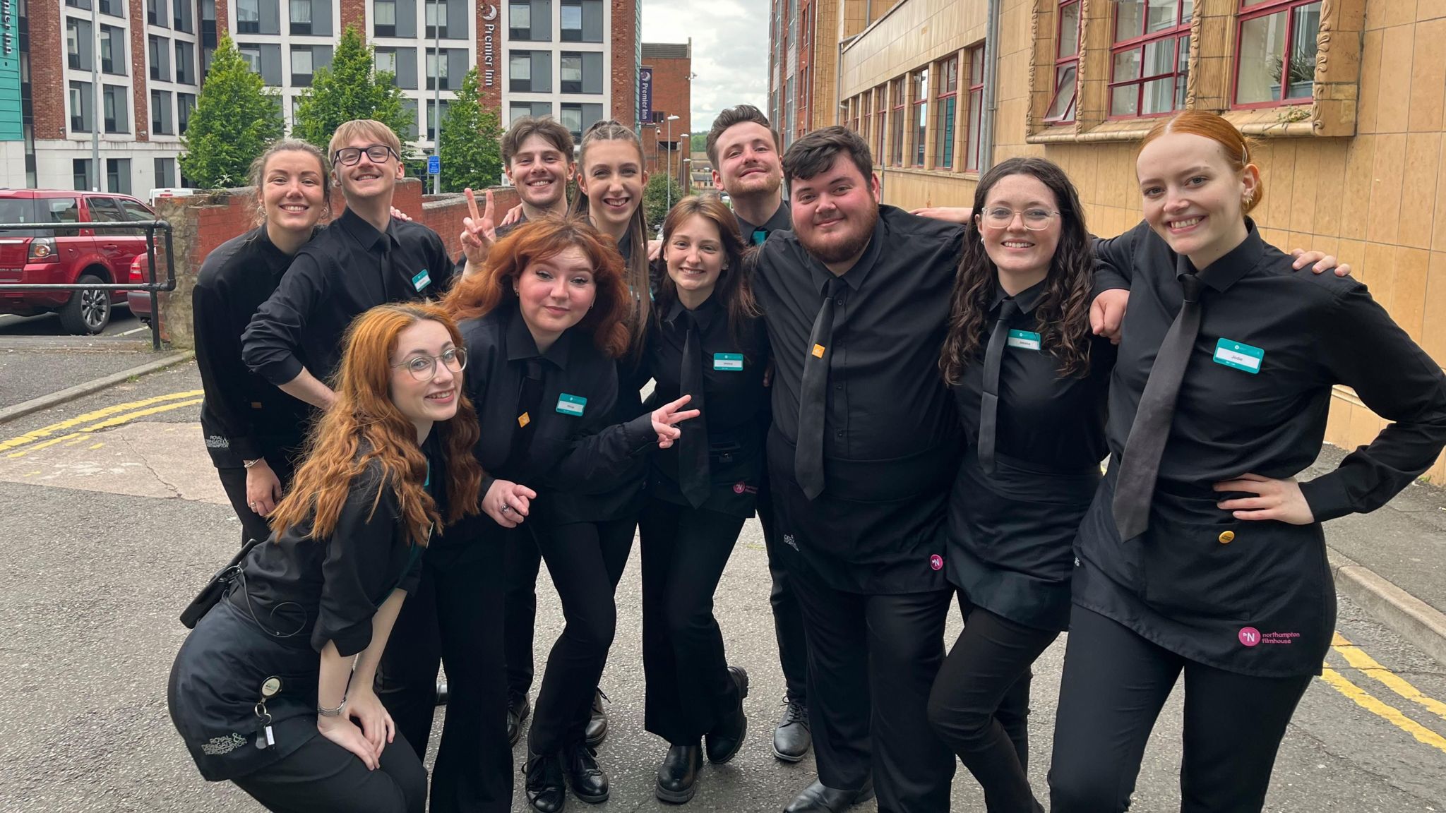 Theatre staff in all black posing outside as a group