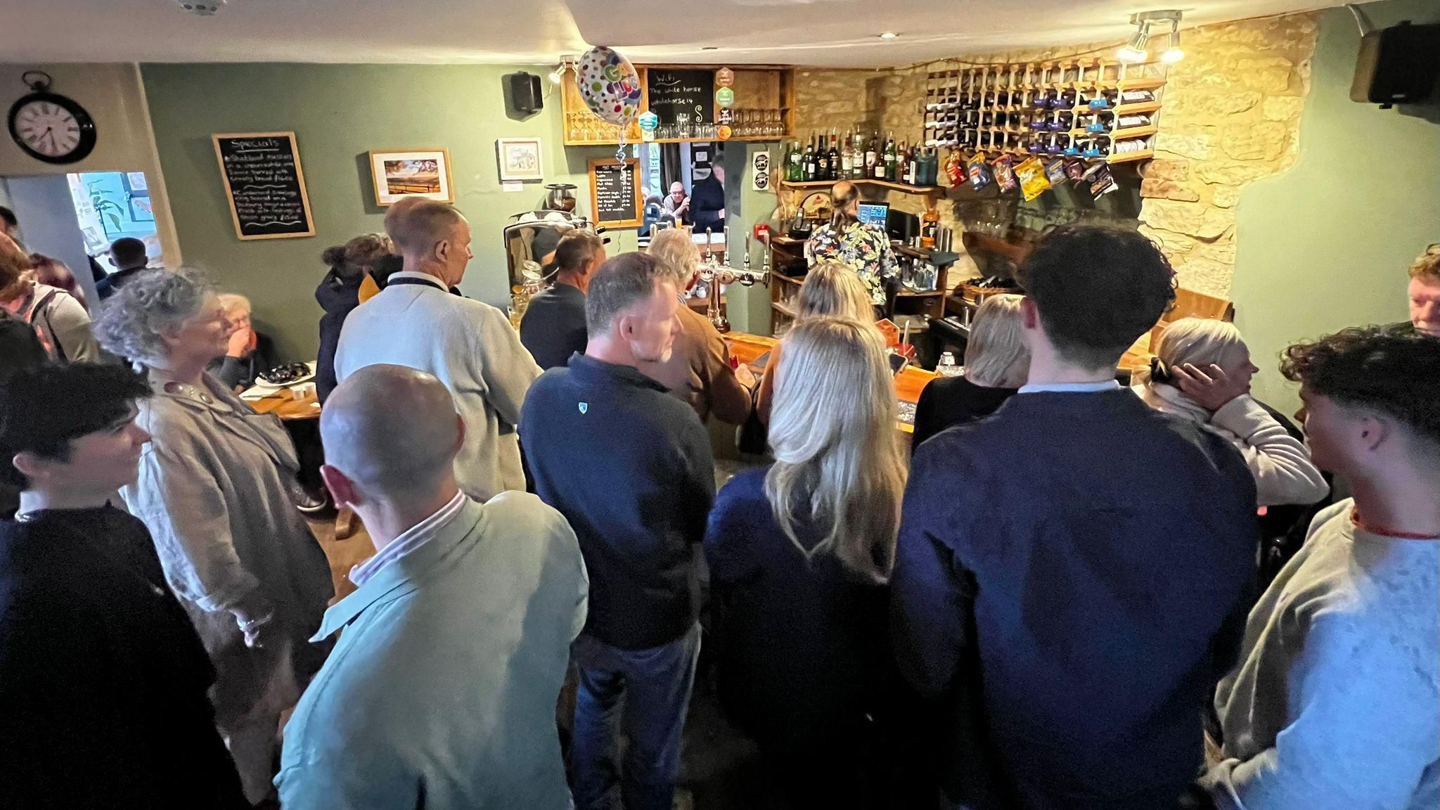 People stand at the bar inside the White Horse pub