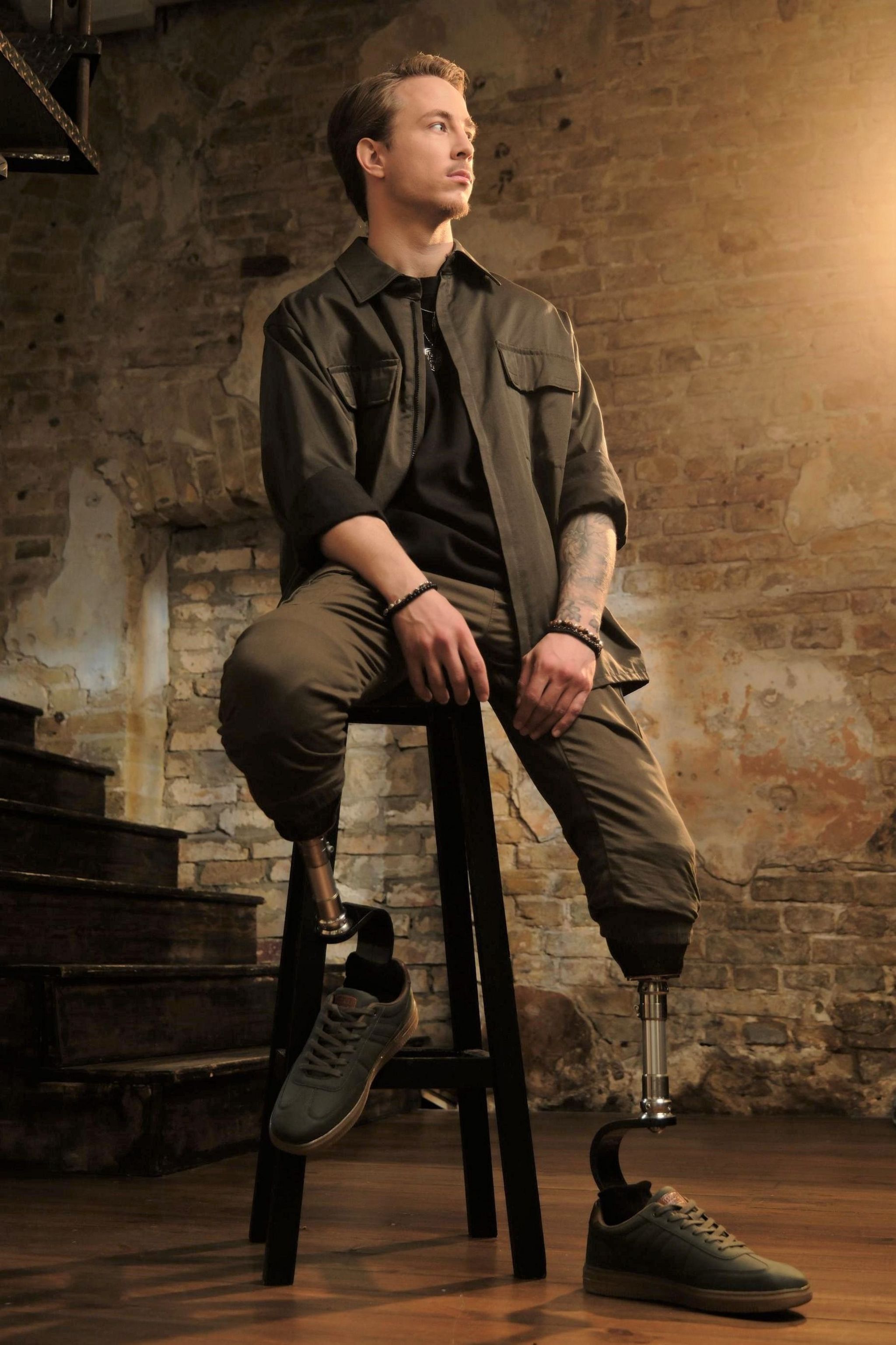 A man with prosthetic legs sits on a stool