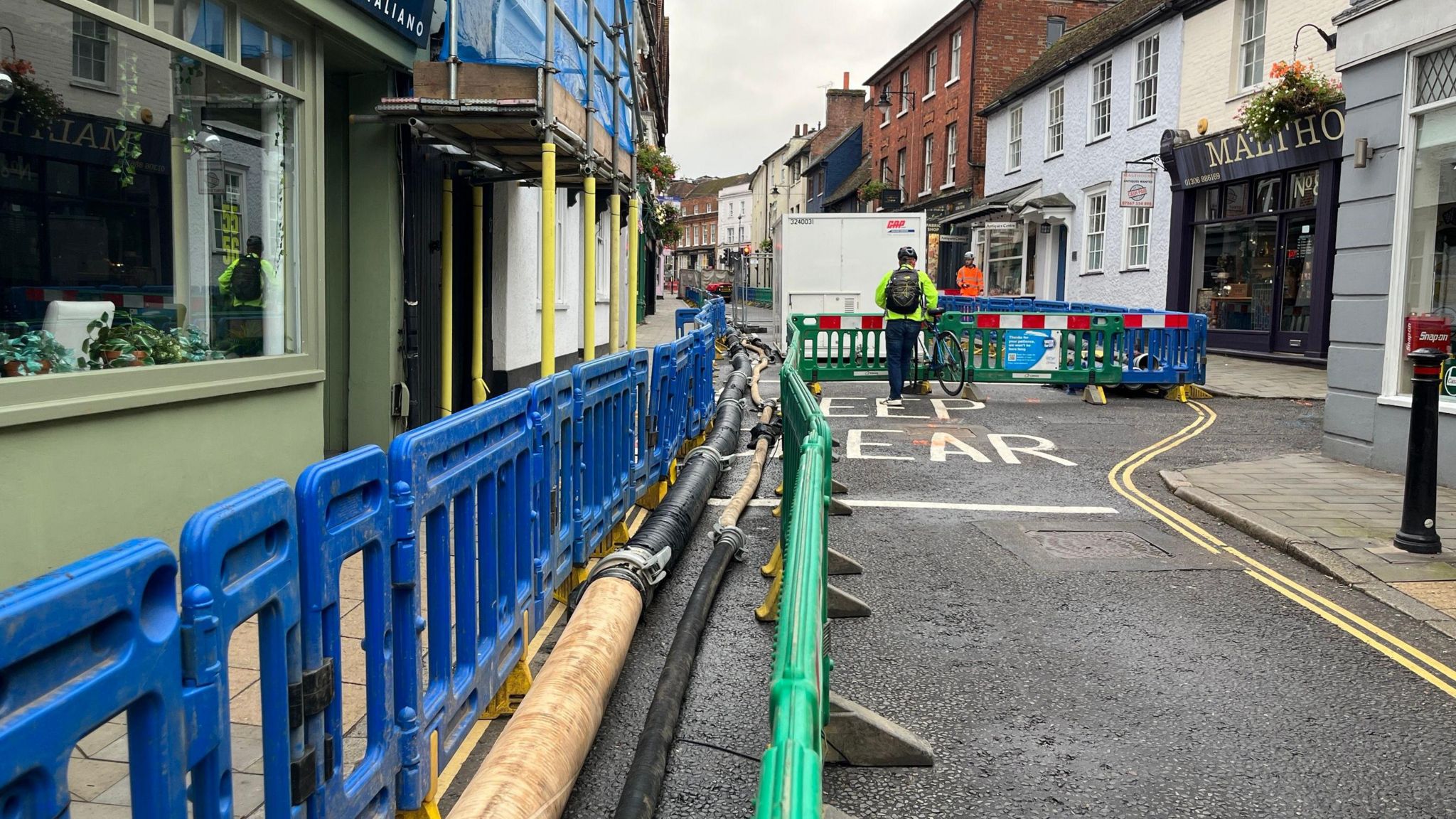 Pipes and fences are seen along West Street in Dorking which is lined with shops