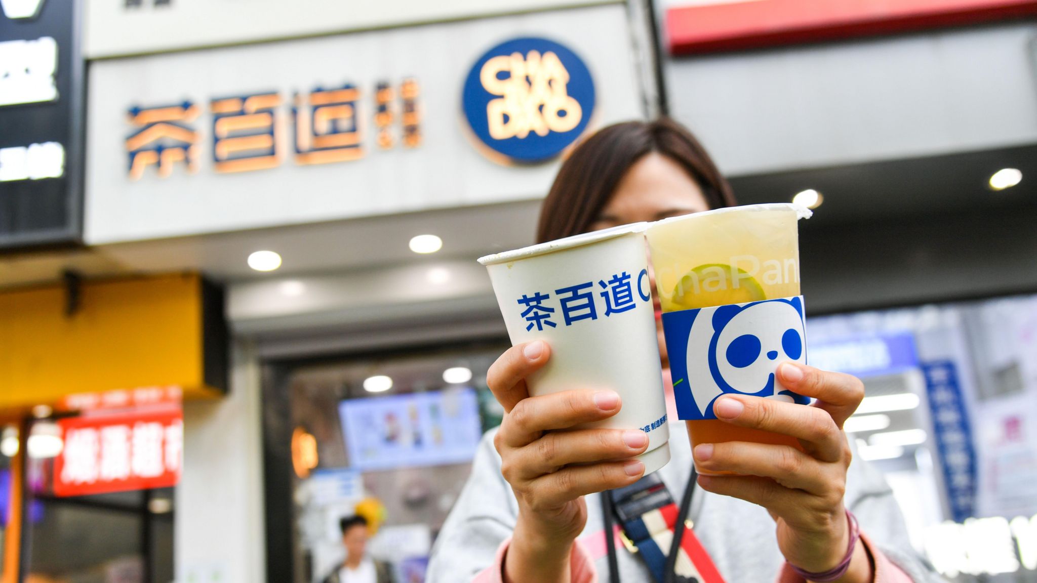 Customer shows her milk tea outside Chabaidao shop in Beijing.