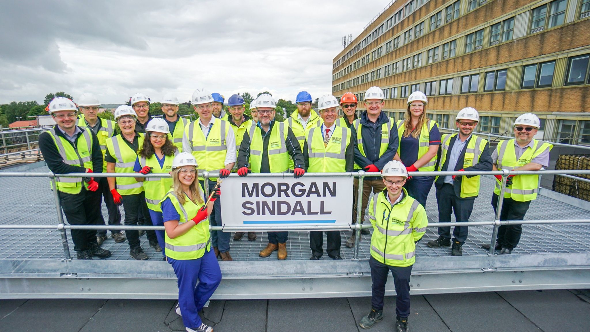 A group of people wearing hard hats and high vis standing on a roof