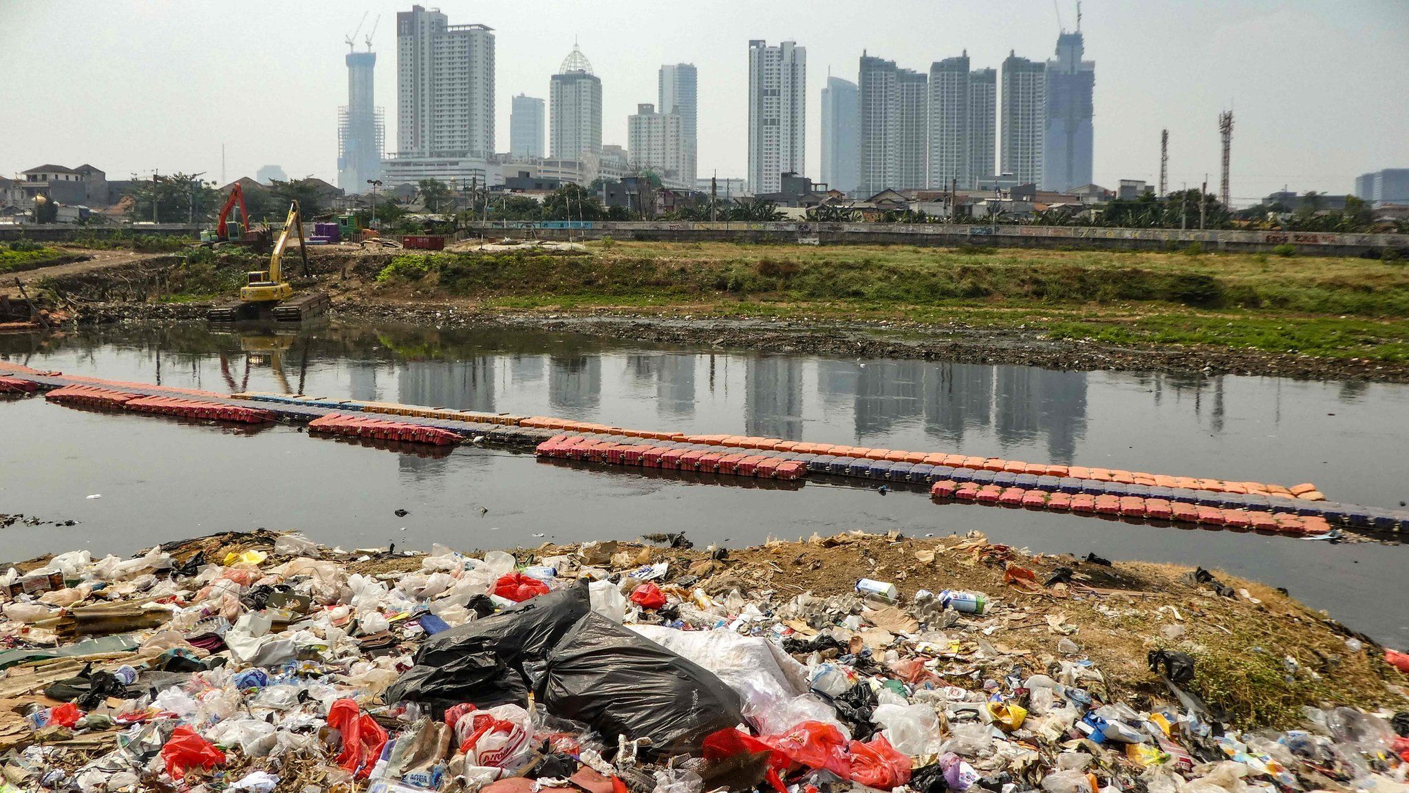 Plastic waste on the banks of a river with a view of the Jakarta skyline (file photo - August 2019)