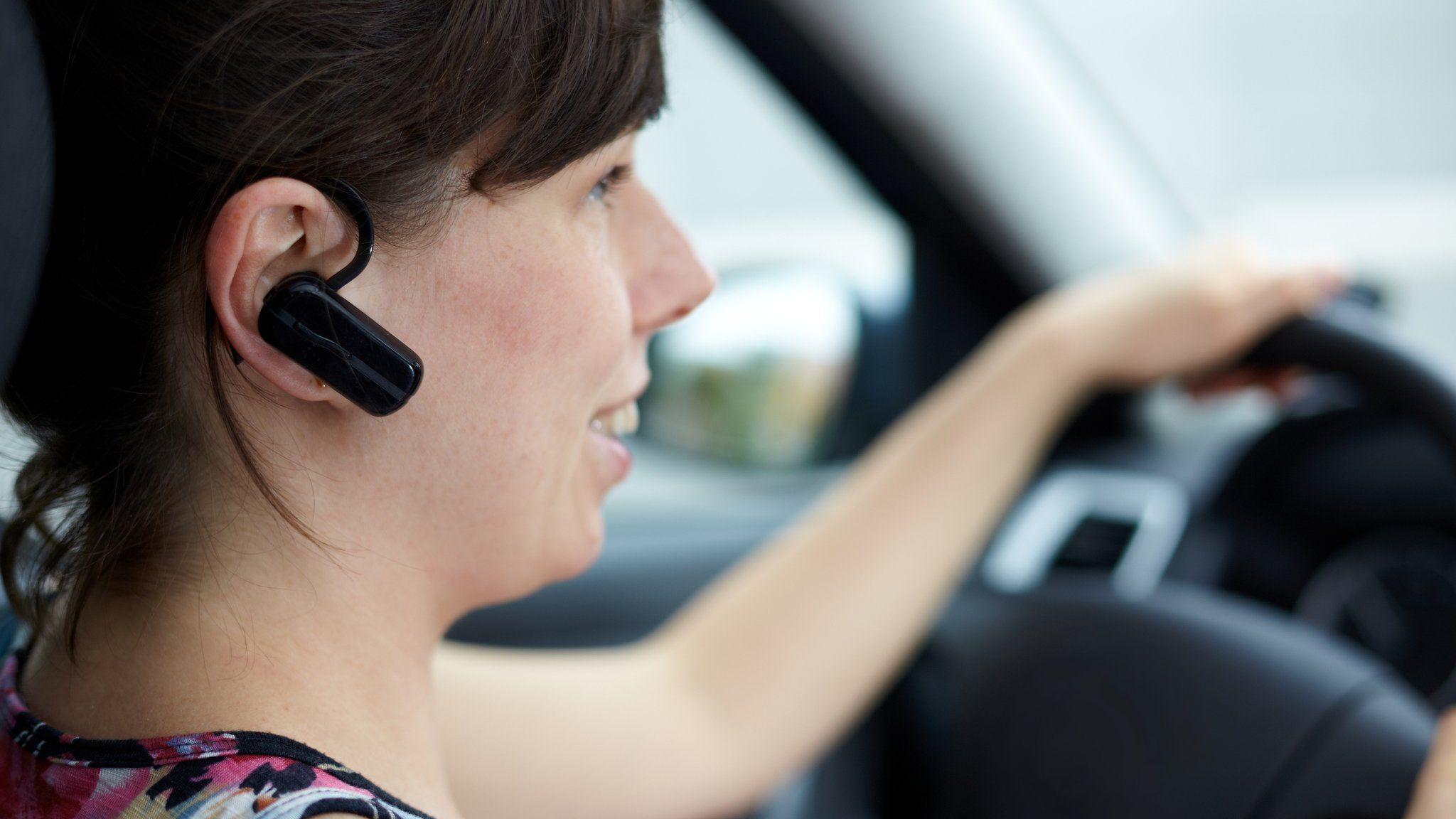 Woman talking in a car with phone headset